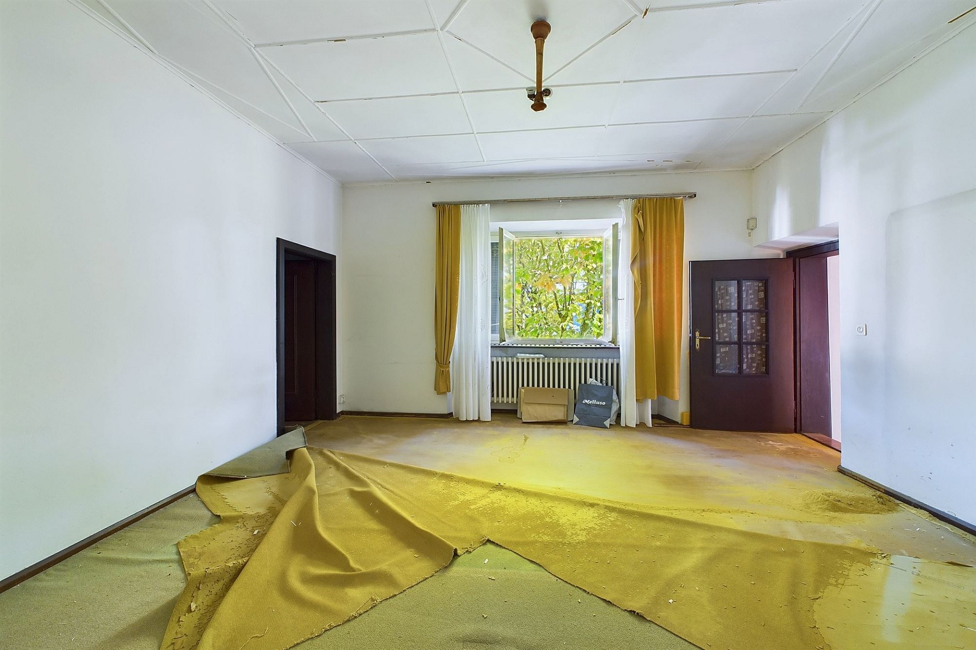 Leerer Wohnraum mit offenem Fenster und abgenutztem Bodenbelag