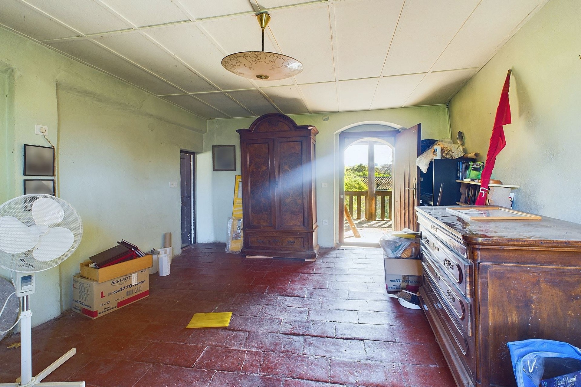 Unordentliches Zimmer mit antiken Möbeln und Balkonzugang