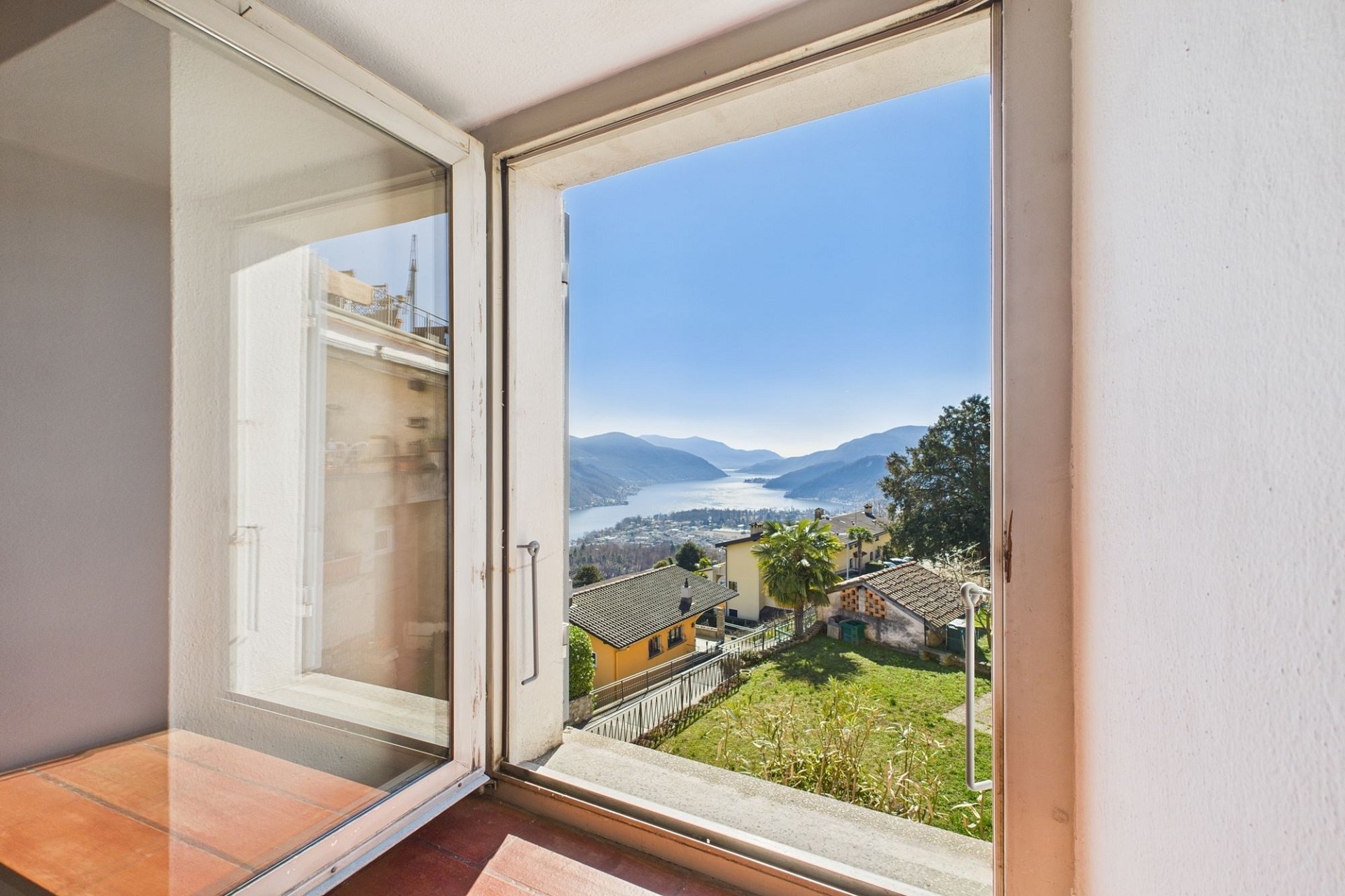 Blick aus einem offenen Fenster auf See und Berge