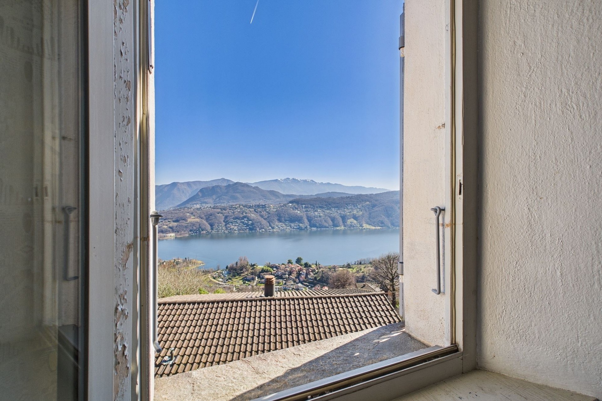 Blick durch ein geöffnetes Fenster auf See und Berge