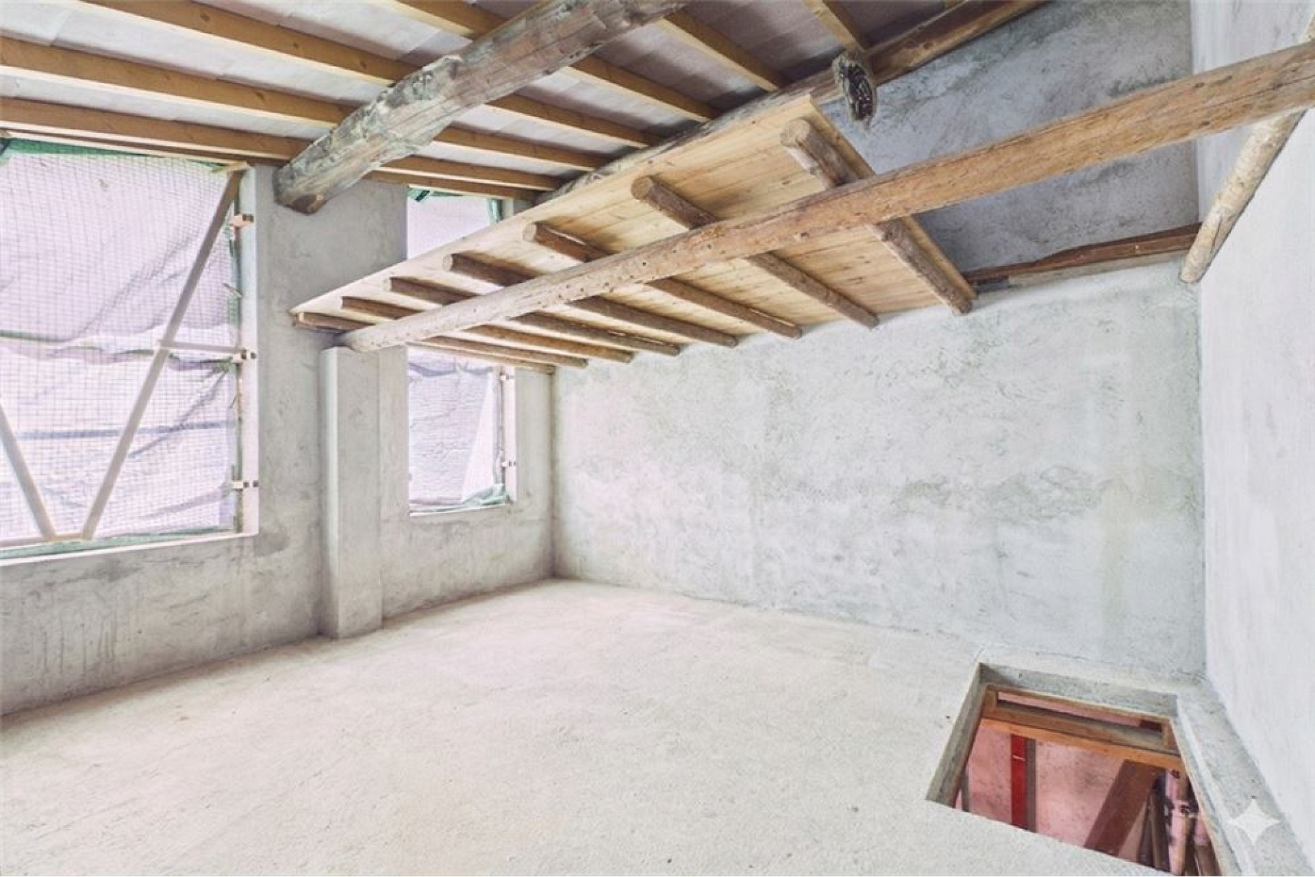 Unfertiger Innenraum mit sichtbarer Holzdecke