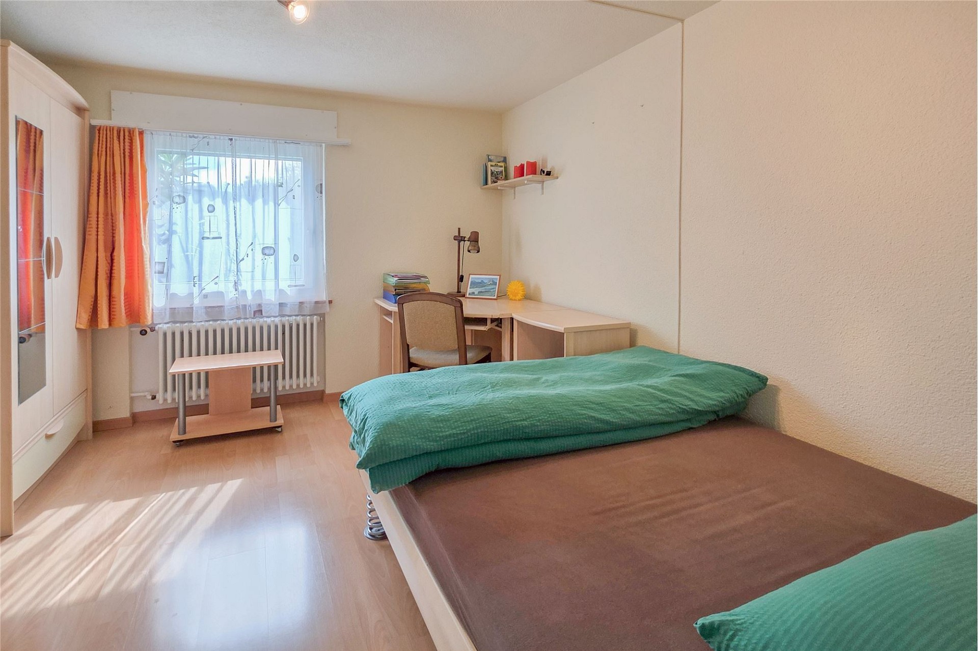 Helles Schlafzimmer mit Einzelbett und Arbeitsplatz