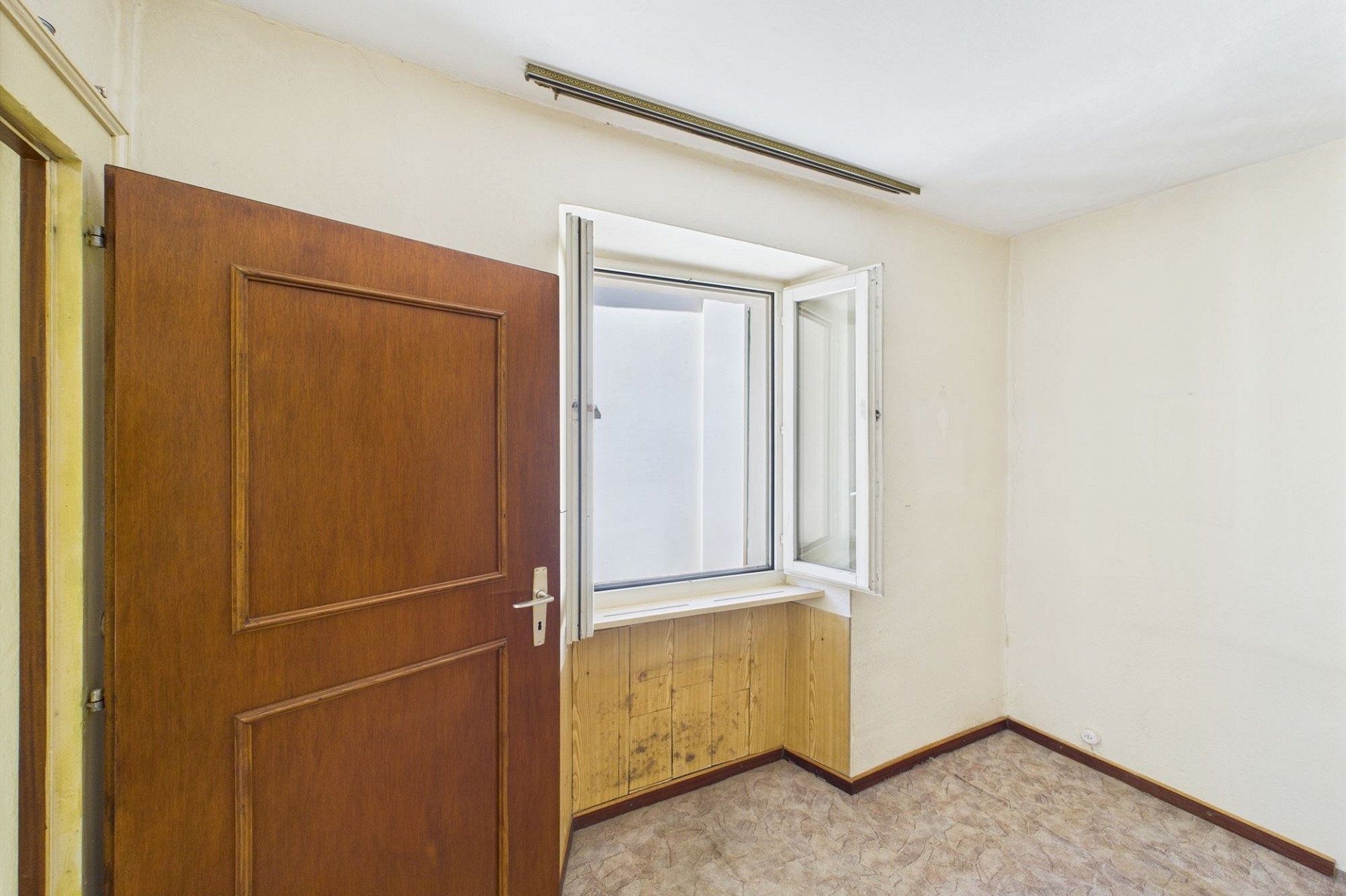 Kleines schlichtes Zimmer mit Fenster und Holztür