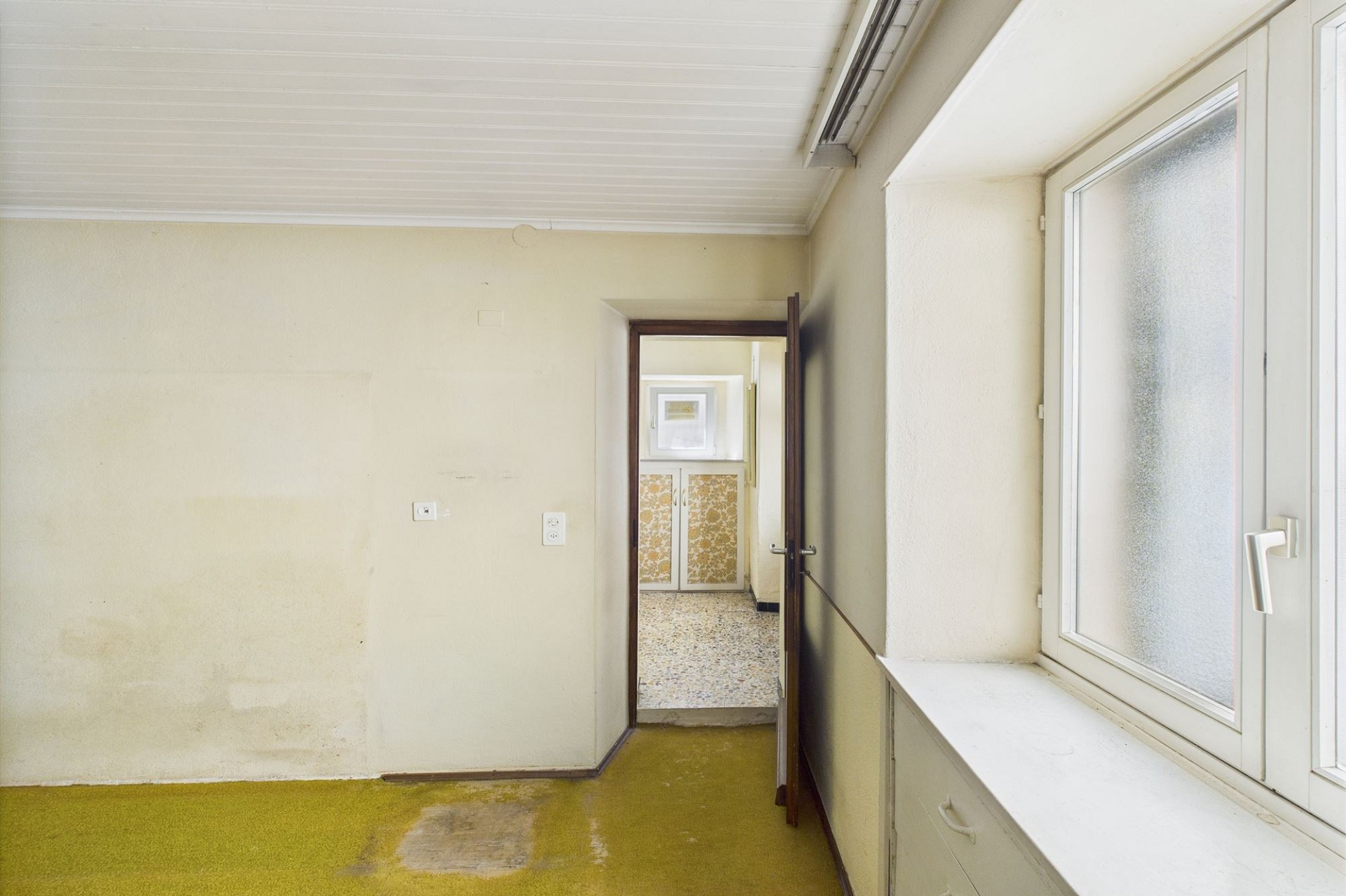 Renovierungsbedürftiger Innenraum mit Flur und Blick in einen Nebenraum