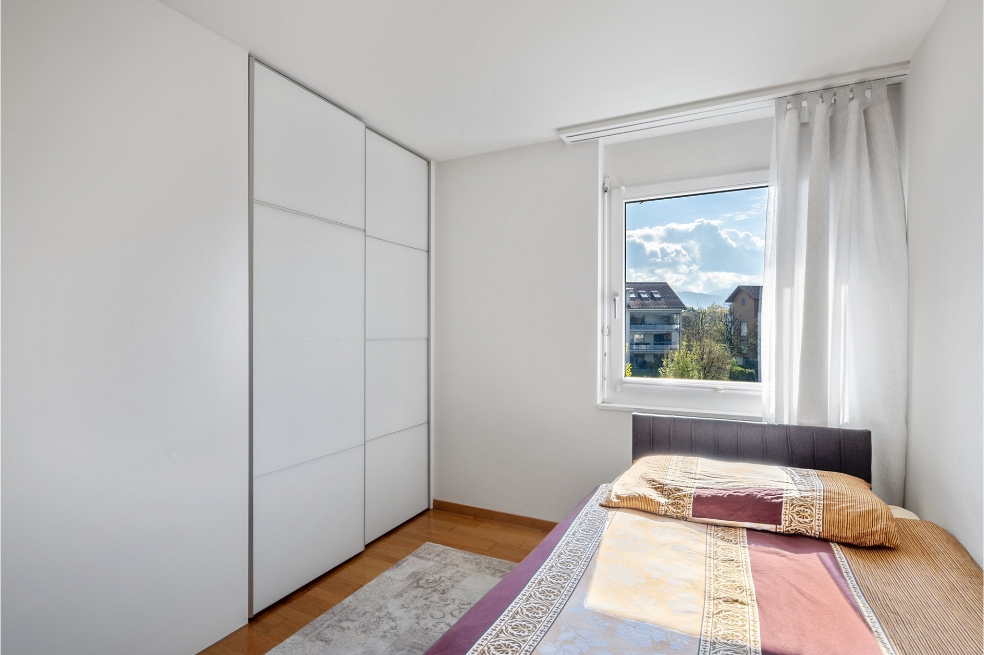 Helles Schlafzimmer mit Einbauschrank und Fensterblick