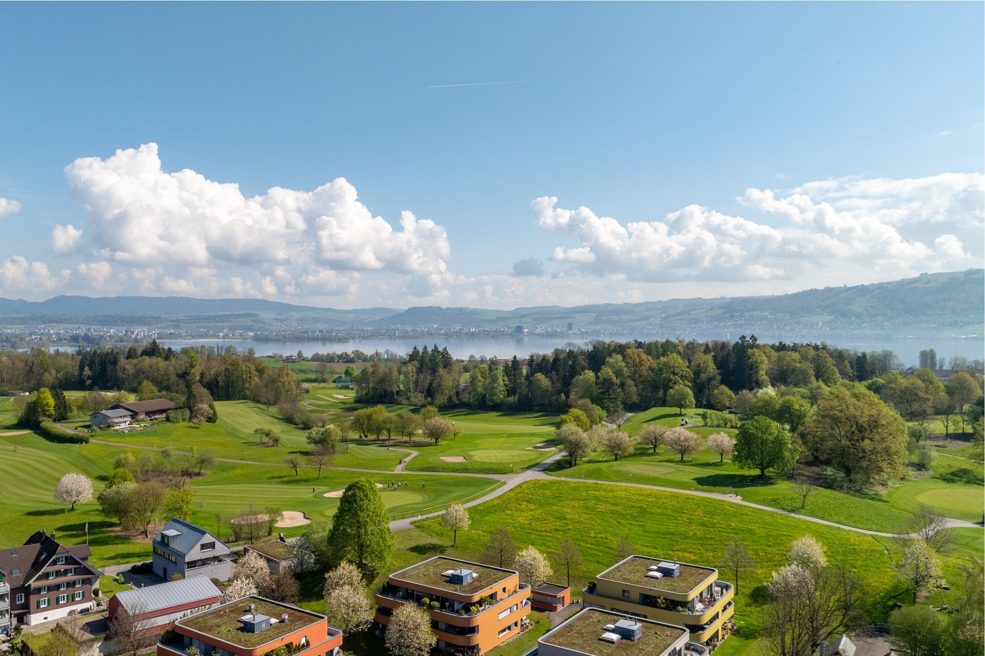 Weitläufige Luftaufnahme mit Seeblick über eine grüne Landschaft