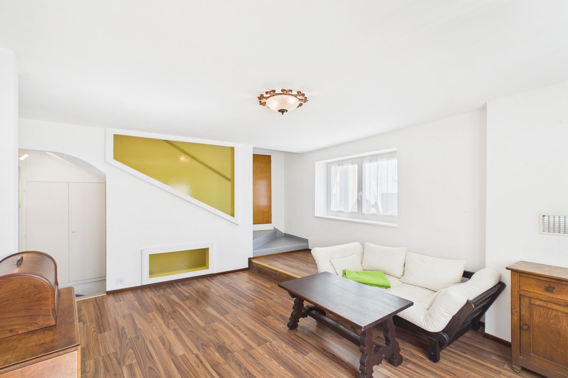 Helles Wohnzimmer mit Treppe und gelben Wandakzenten