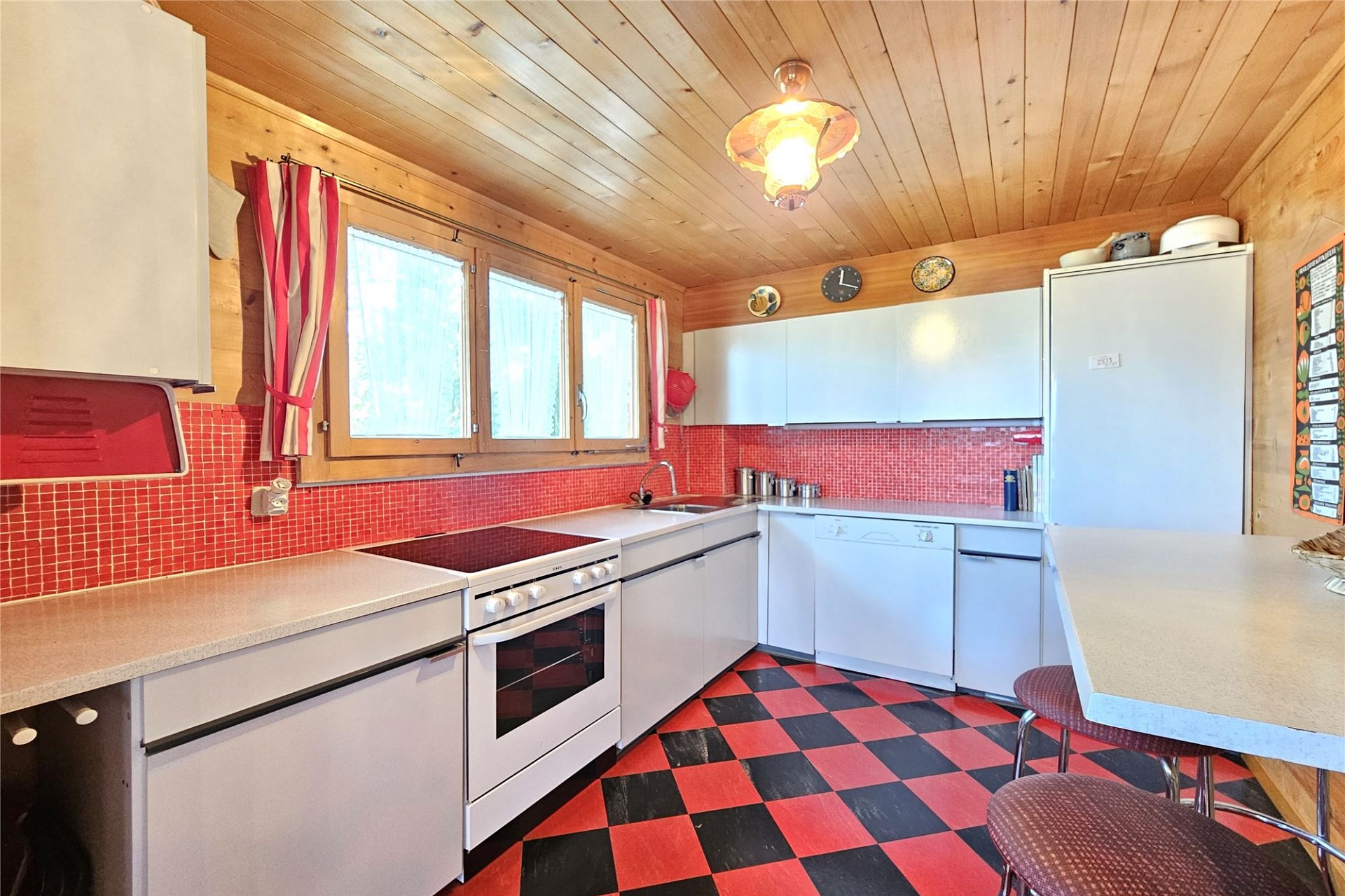 Kompakte Küche mit Holzvertäfelung und Rot-Schwarz-Boden