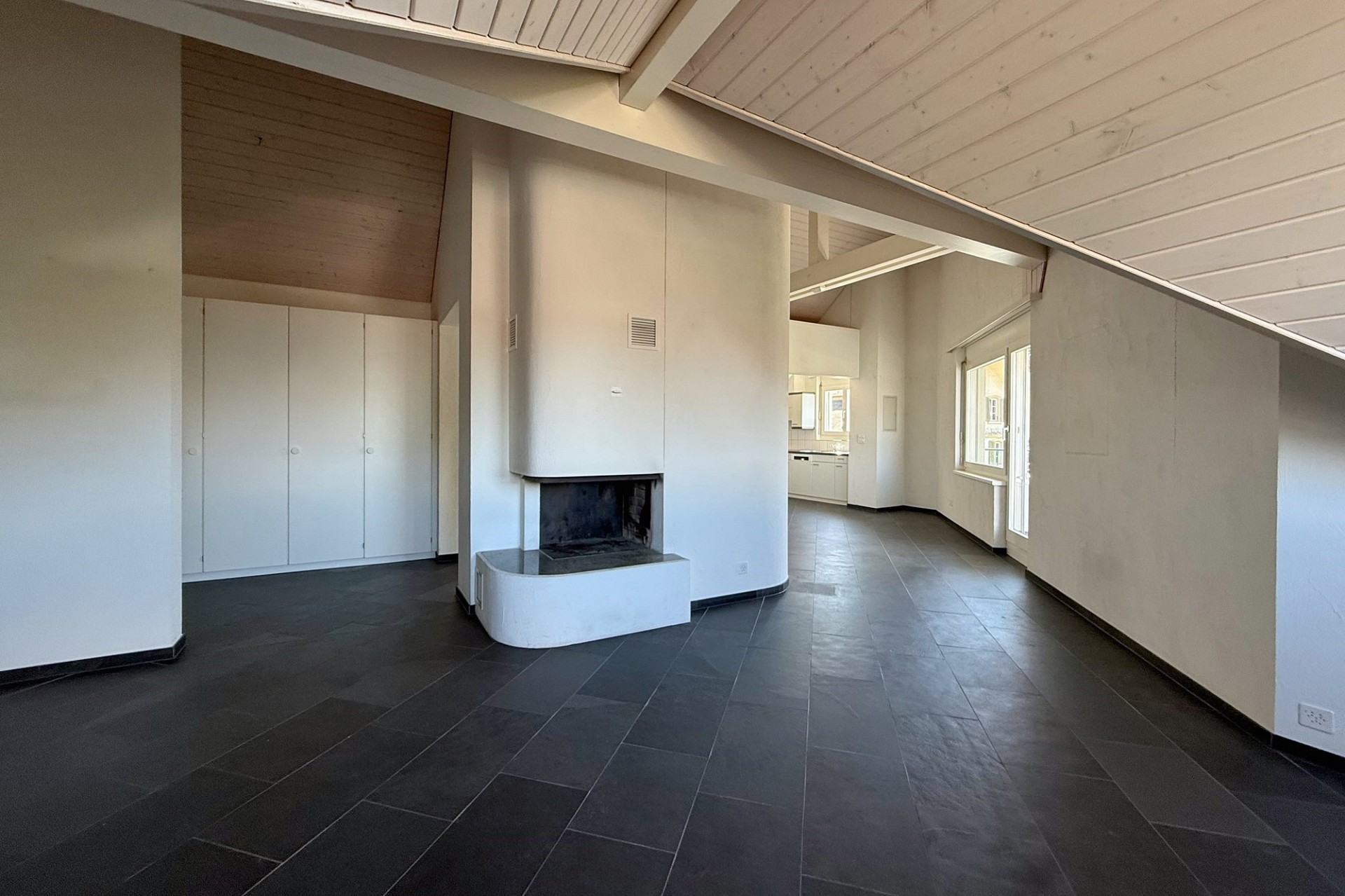 Großer heller Wohnbereich mit Kamin und sichtbarer Dachschräge