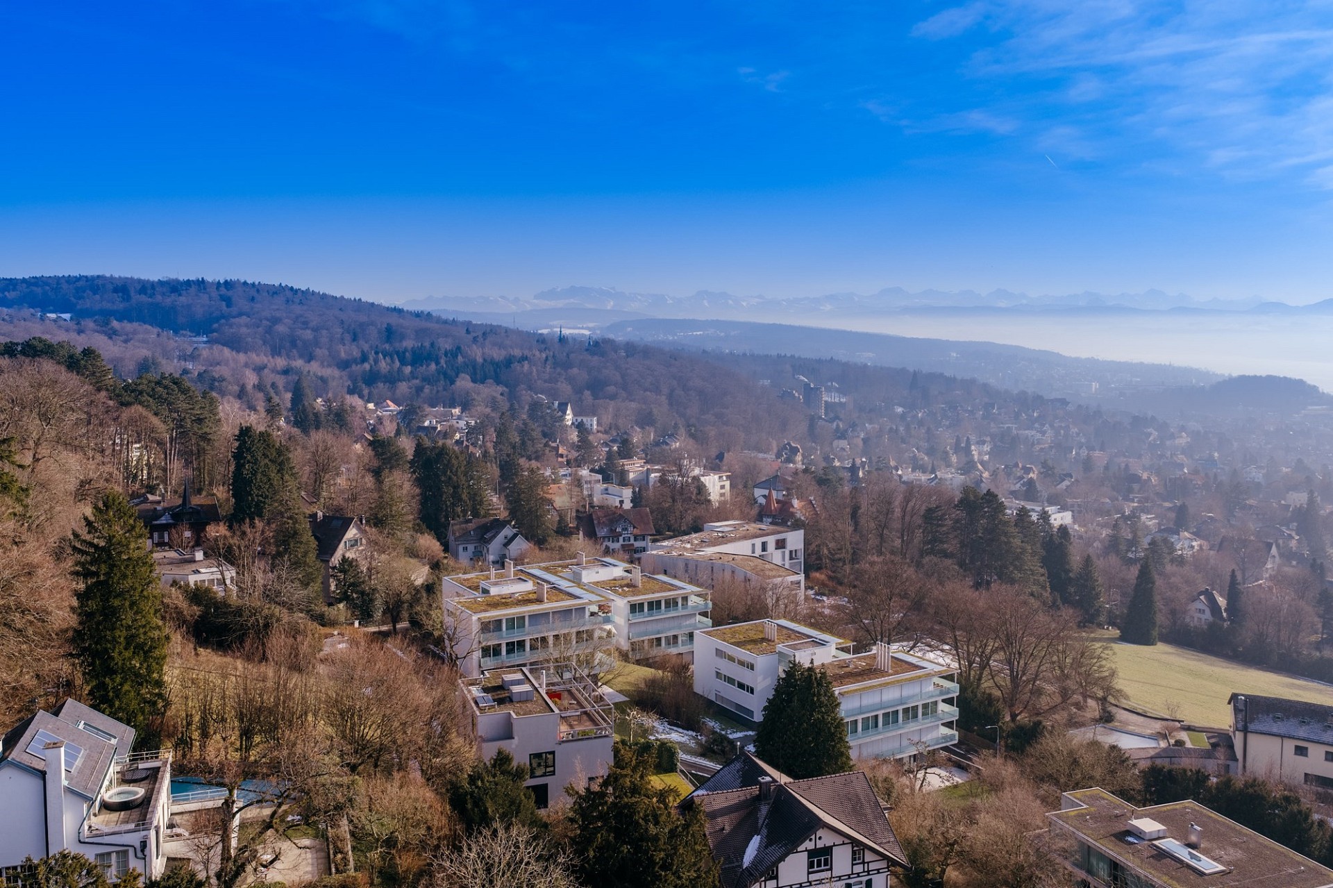Luftaufnahme eines Hangs mit Stadt- und Bergpanorama