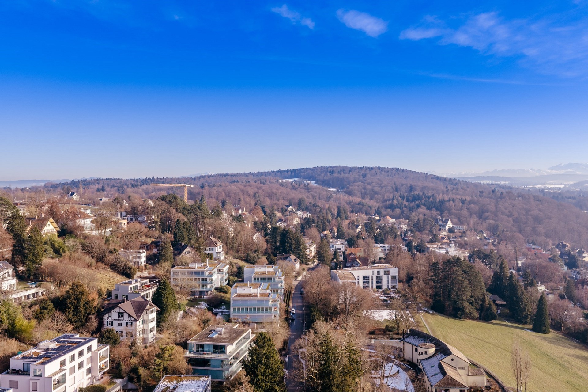 Luftaufnahme eines hügeligen Wohngebiets mit Bergblick