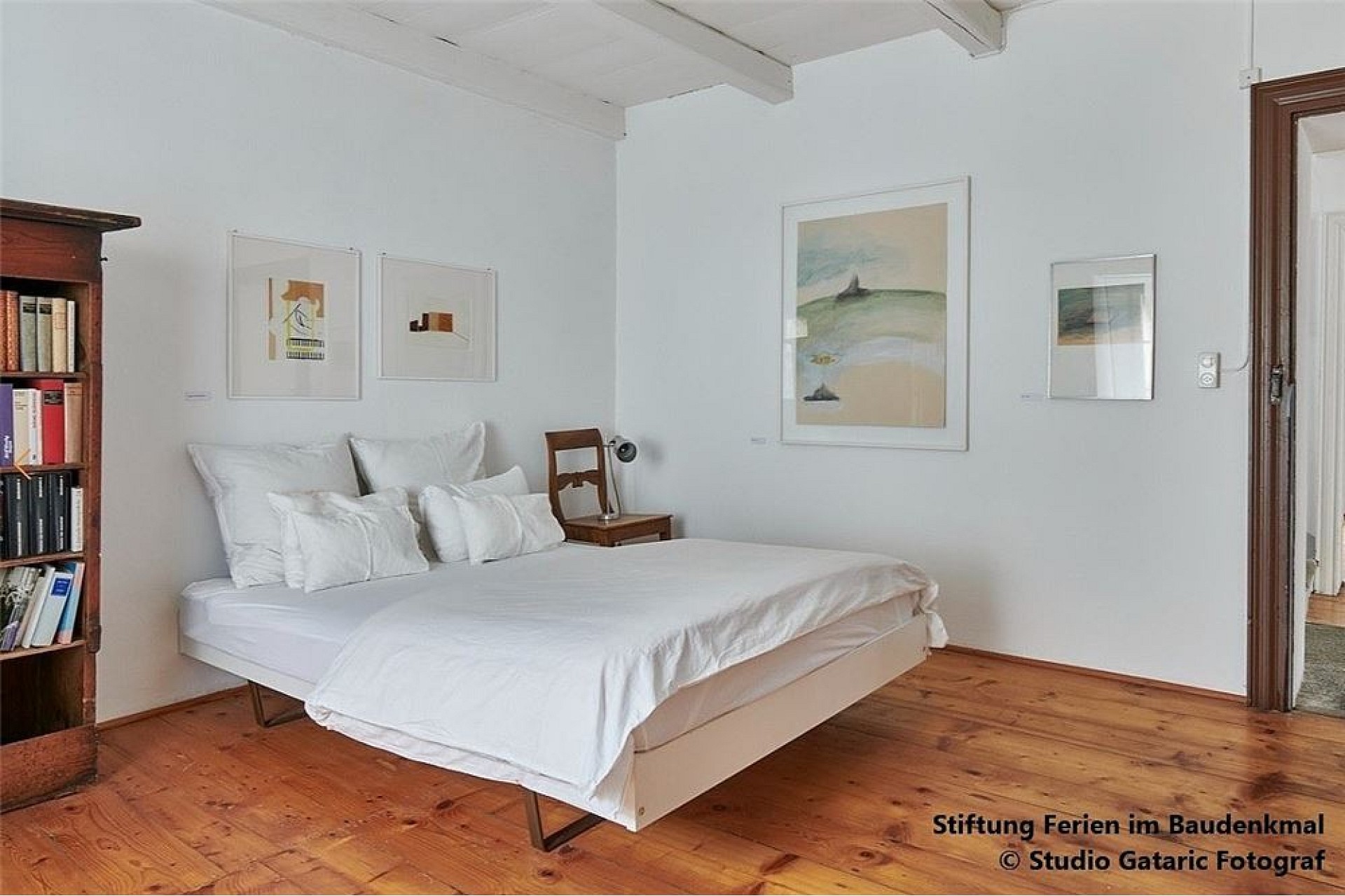 Helles Schlafzimmer mit Holzboden und Kunstwerken