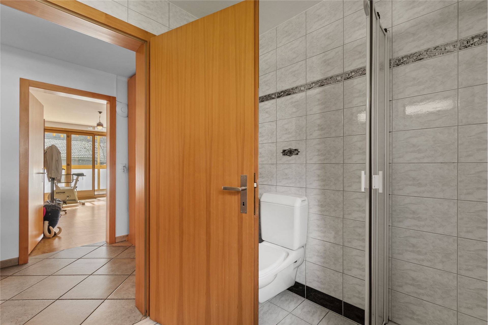 Badezimmer mit offener Tür und Blick in angrenzenden Raum