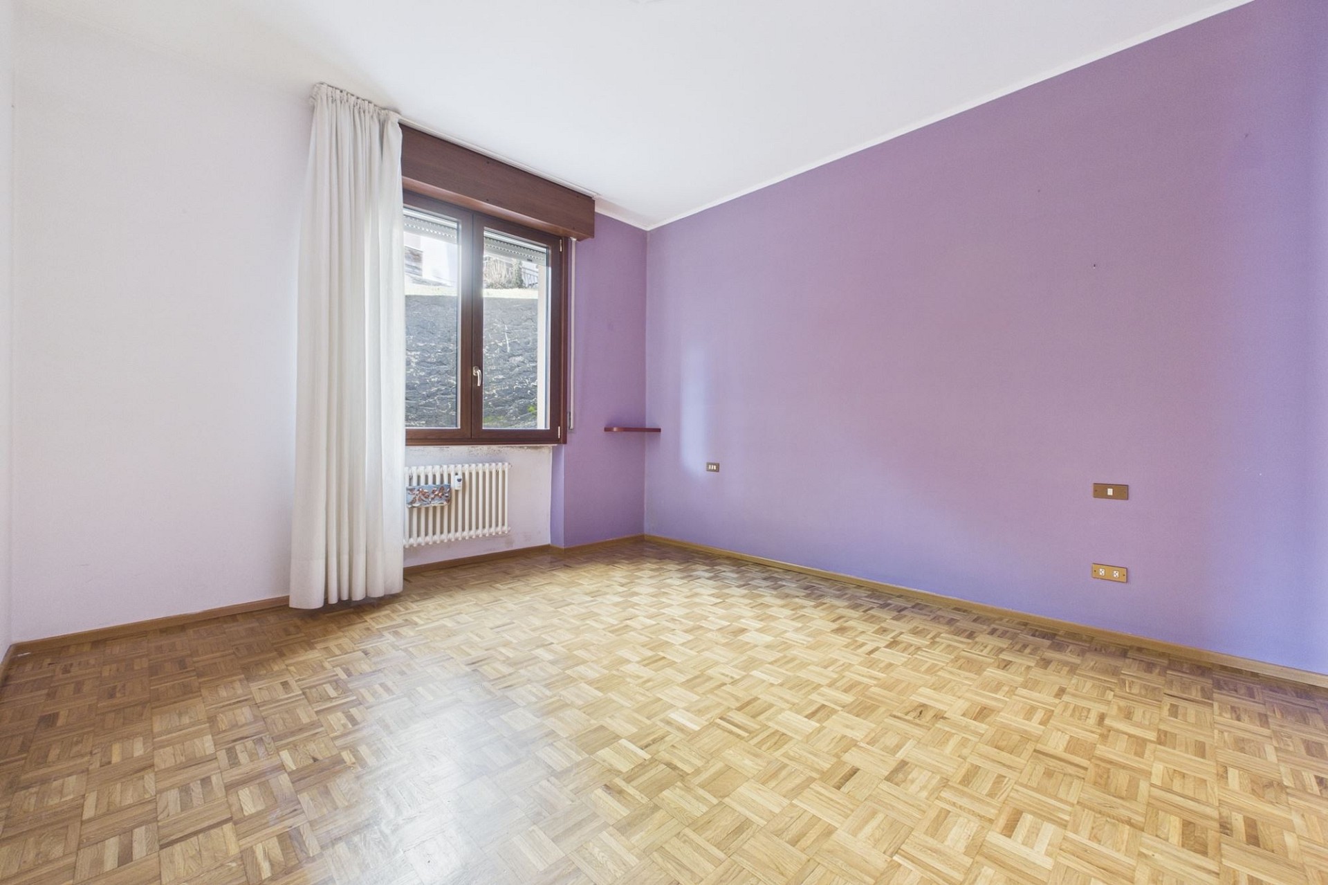 Leeres Zimmer mit lila Wänden und Parkettboden