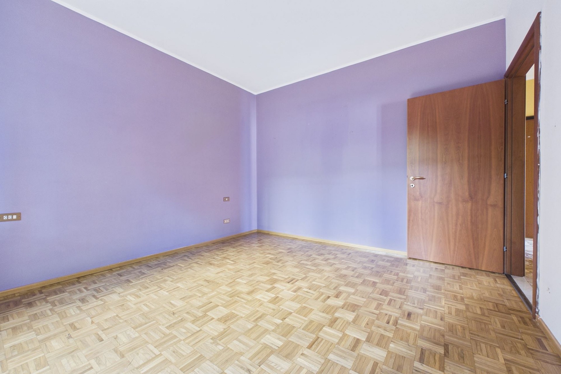 Leerer Raum mit lila Wänden und Holztür