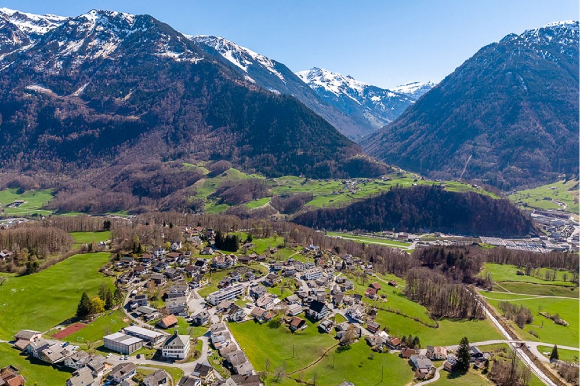 Luftaufnahme eines alpinen Tals mit Dorf