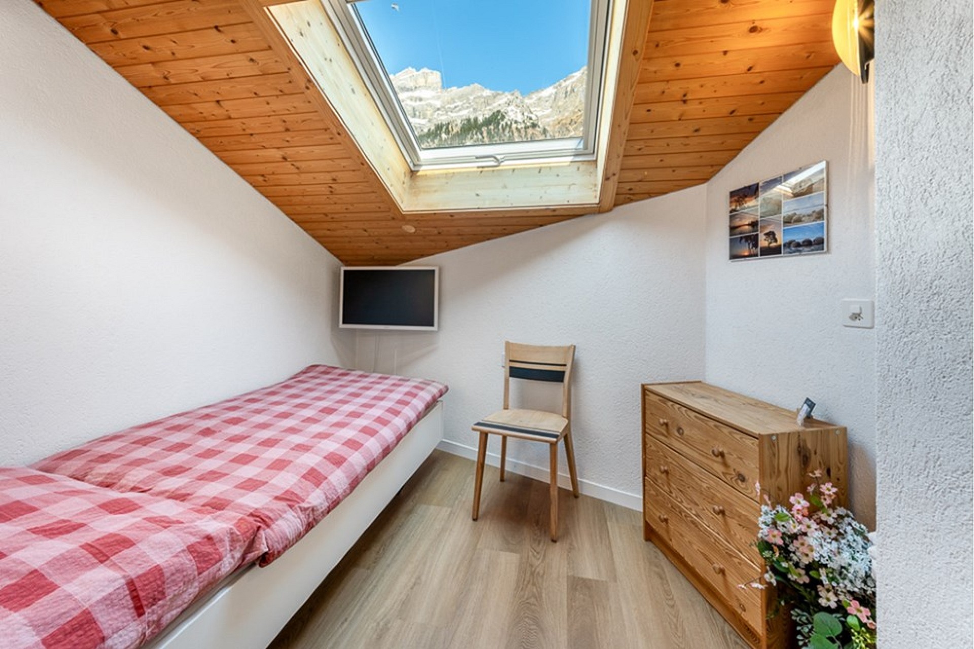 Kleines Dachgeschoss-Schlafzimmer mit Dachfenster und Bergblick