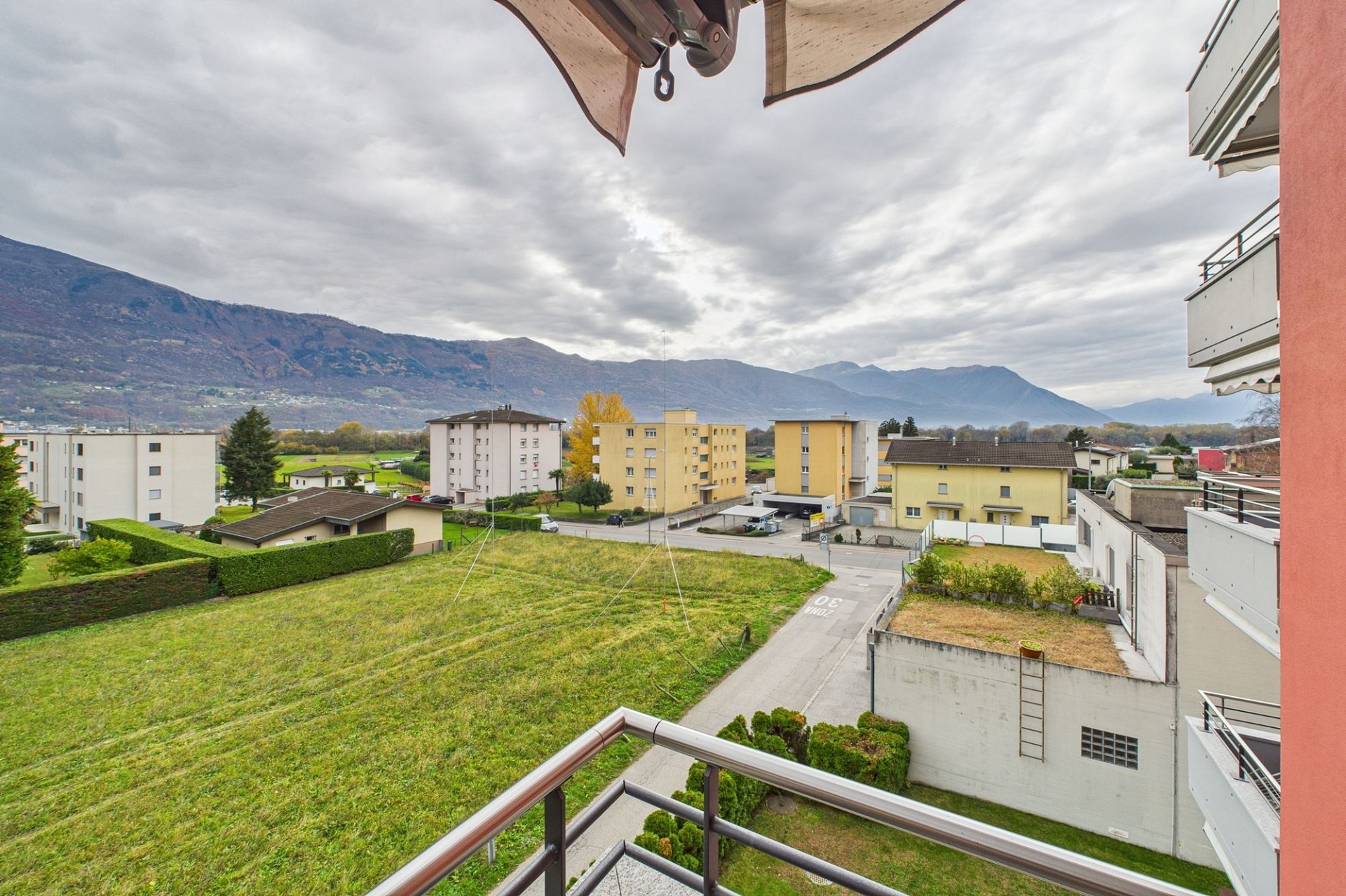 Balkonblick über Wohnhäuser ins Tal mit Bergen