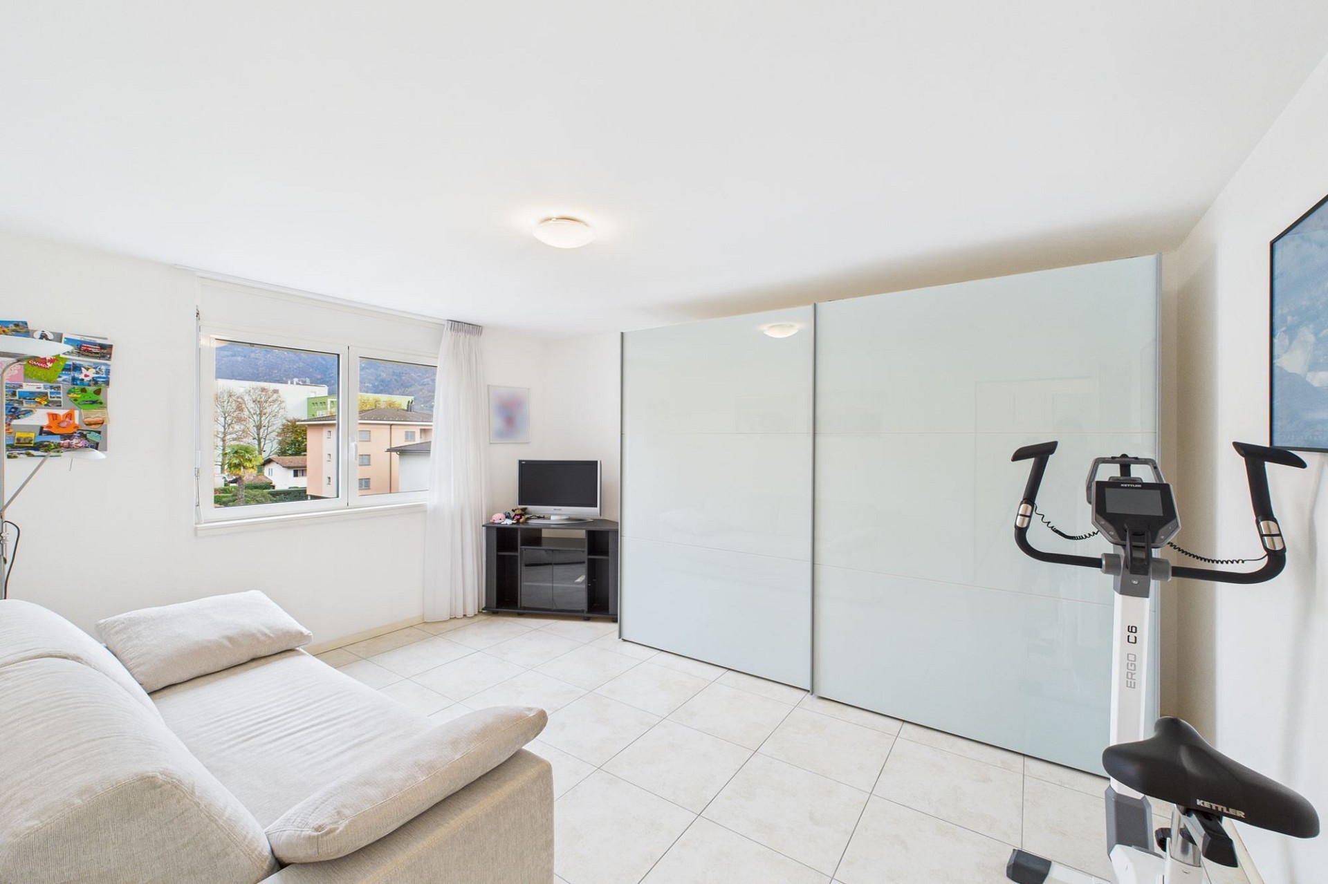 Helles Zimmer mit Fitnessgerät und Schrankwand