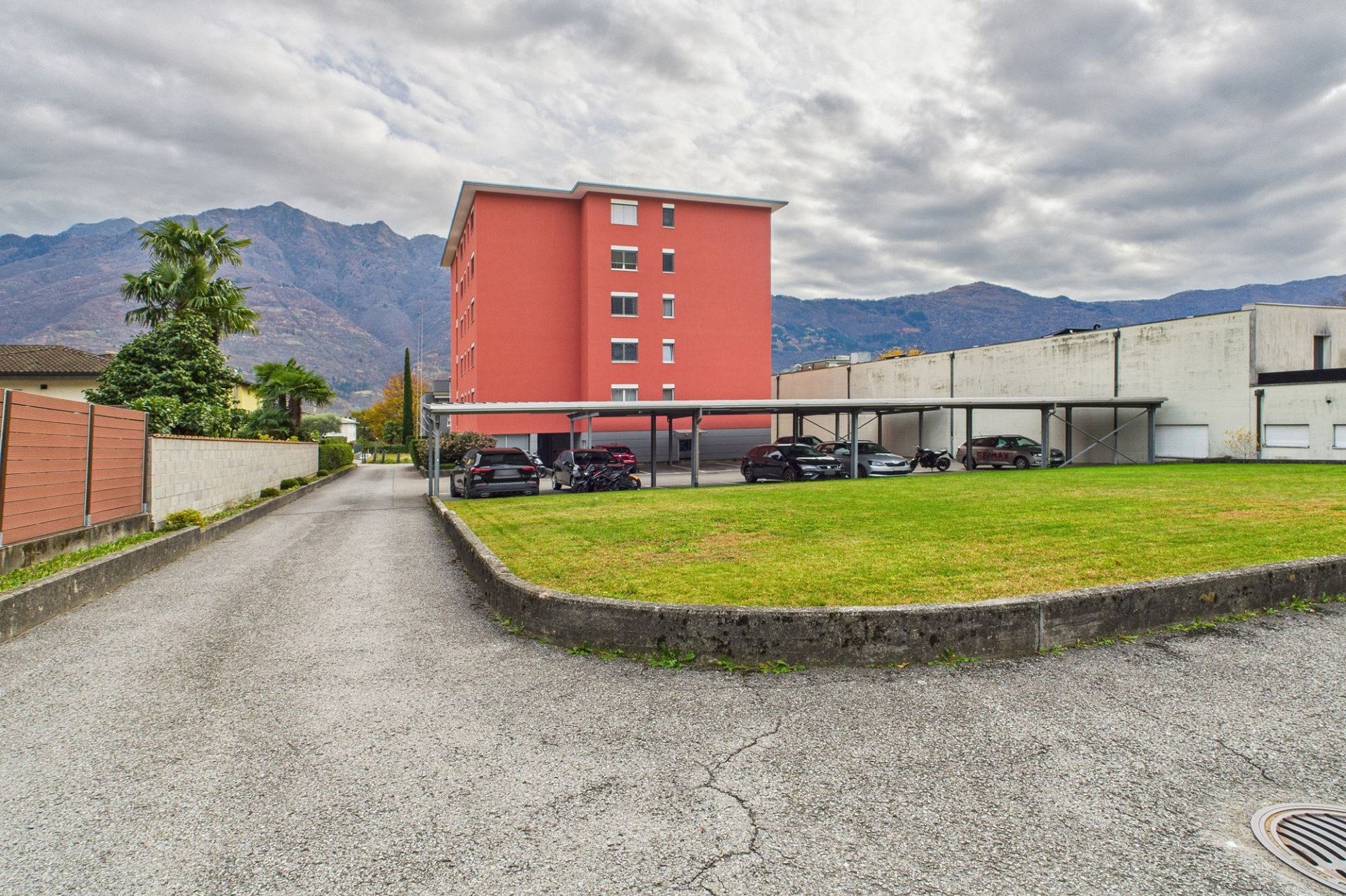 Außenansicht eines Wohn- oder Mehrfamilienhauses mit Parkplatz und Bergkulisse