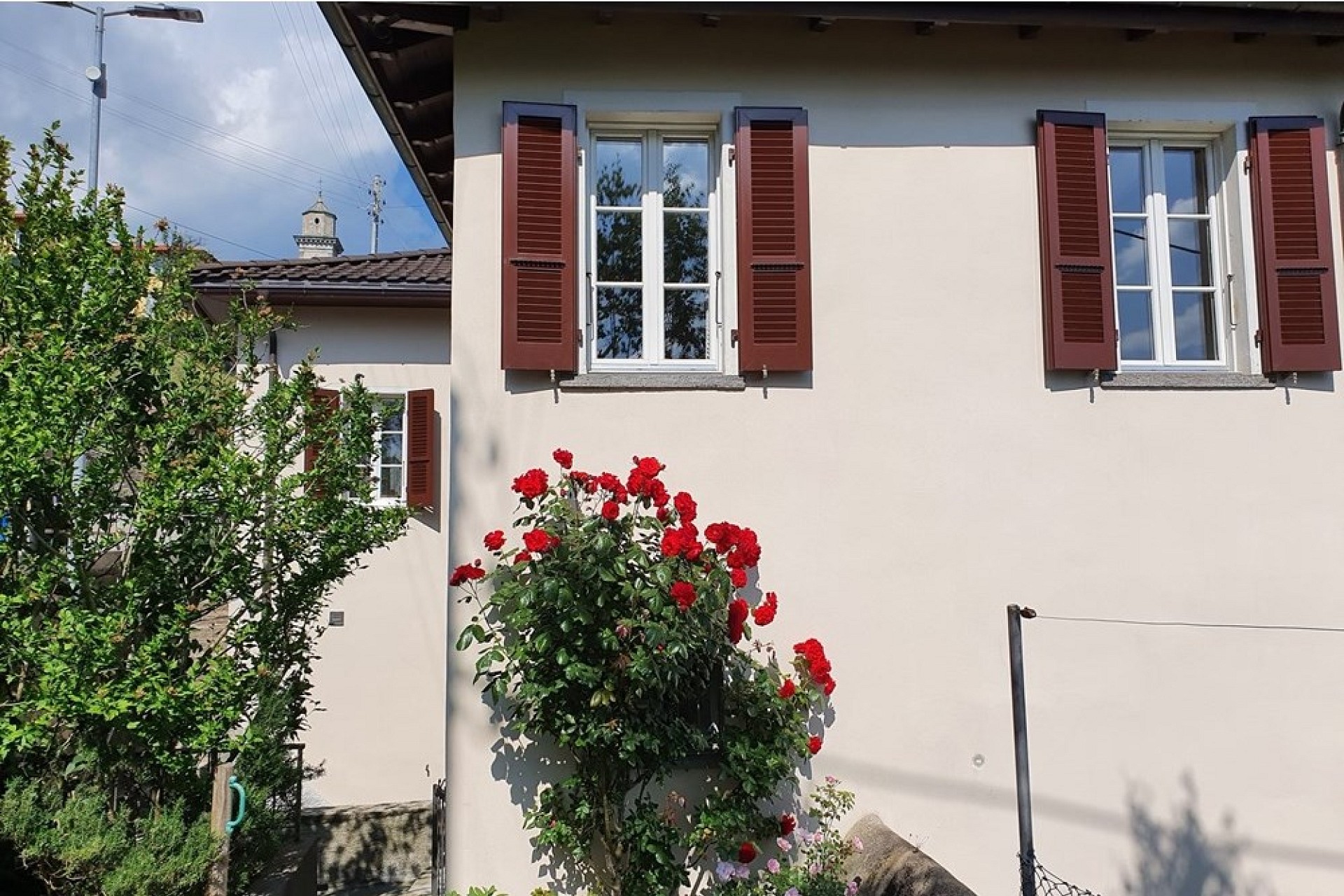 Außenansicht eines Wohnhauses mit Fensterläden und Garten