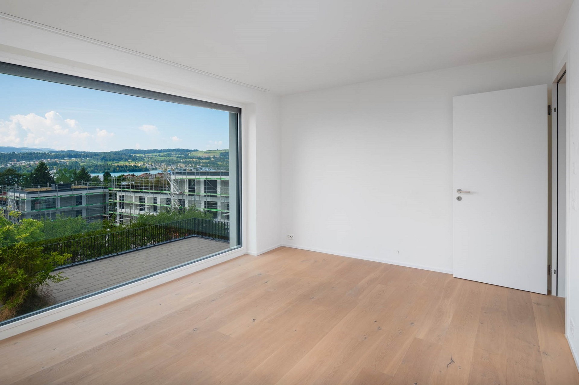 Leerer heller Raum mit Panoramafenster und Blick ins Grüne