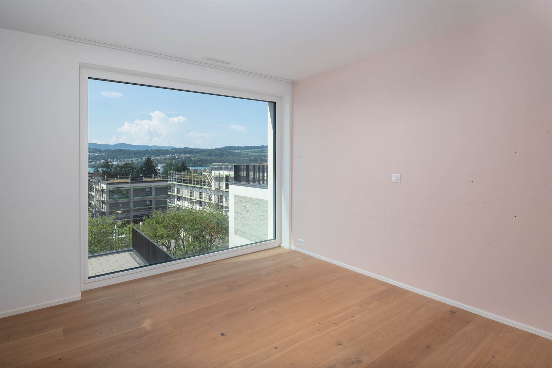 Leeres helles Zimmer mit großem Panoramafenster und Blick ins Grüne