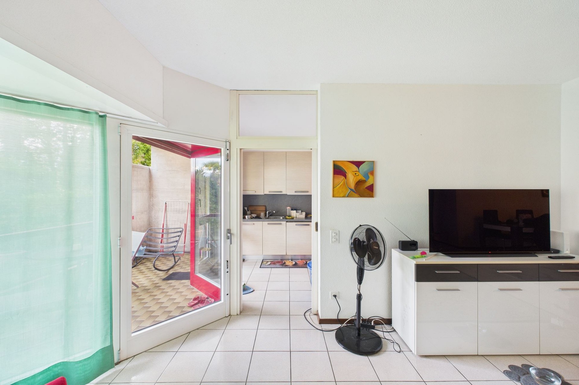 Heller Wohnraum mit Zugang zu Balkon und Blick in die Küche