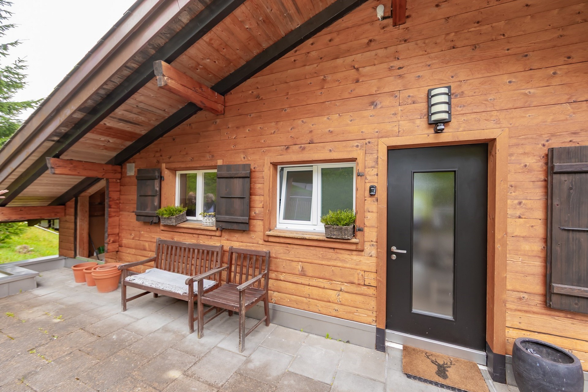 Holzverkleidete Hausfassade mit überdachter Terrasse