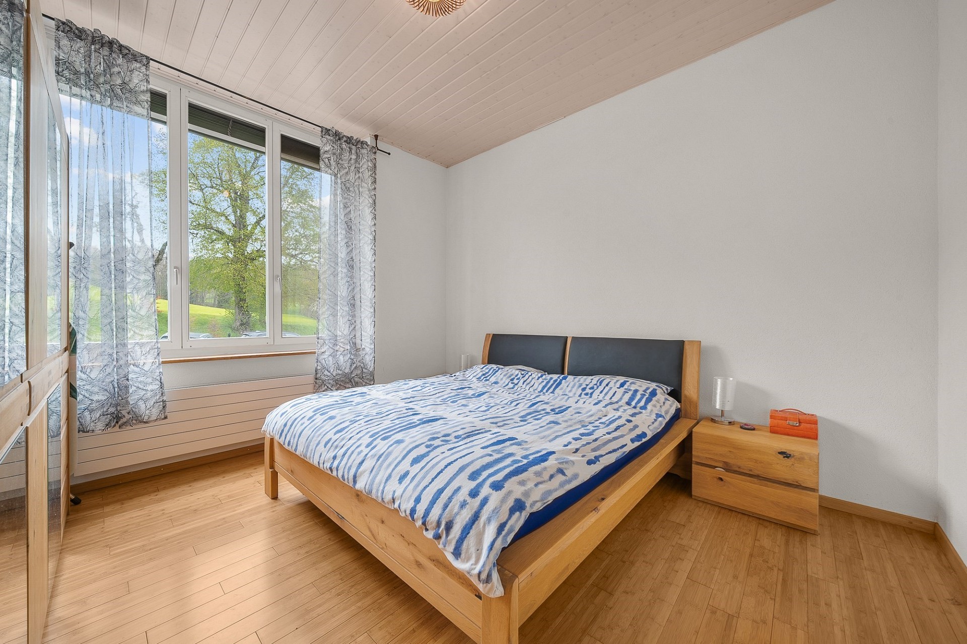 Helles Schlafzimmer mit Holzoptik und Blick ins Grüne