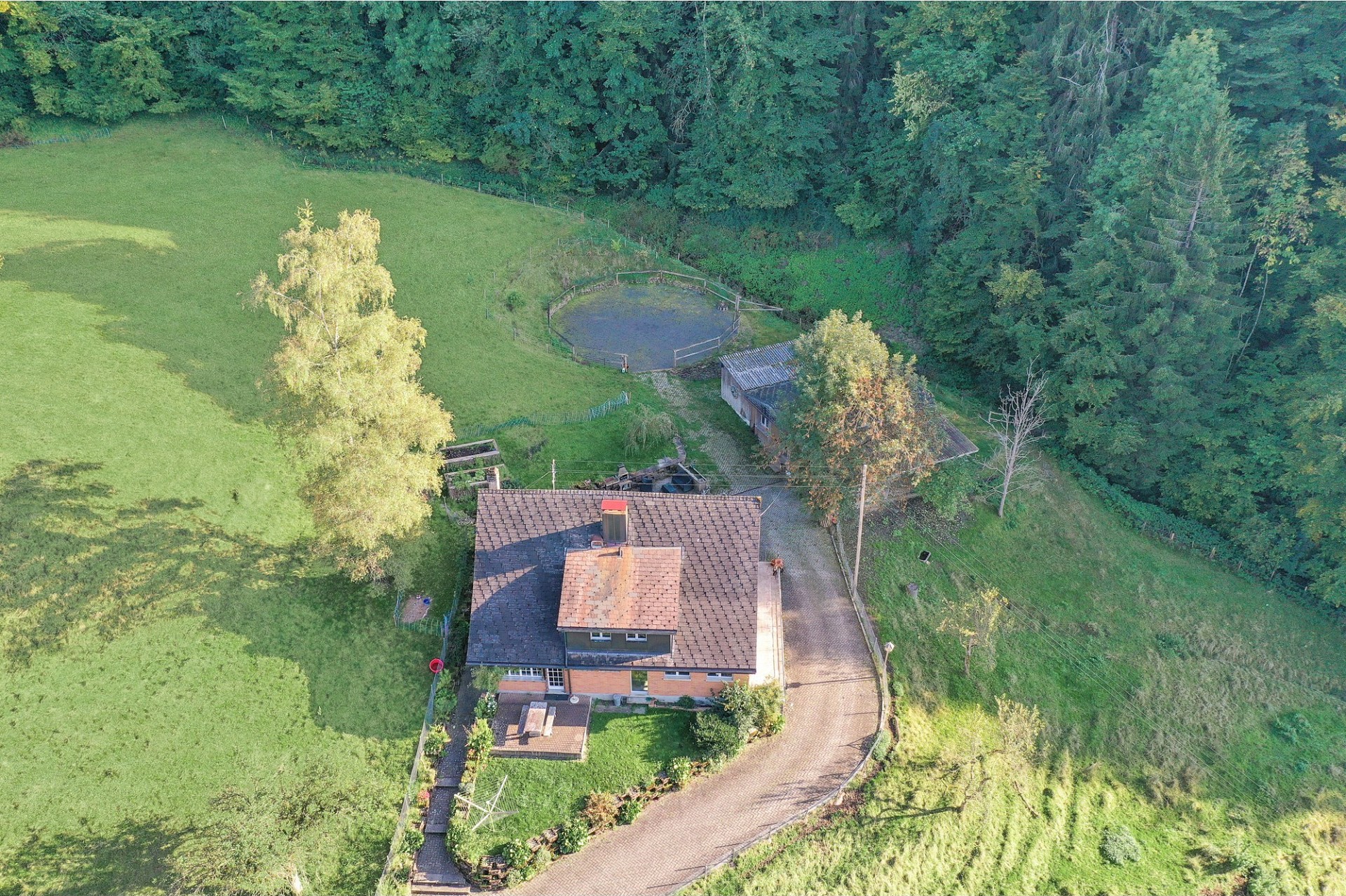 Luftaufnahme eines ländlichen Anwesens mit Haus, Hof und Weide