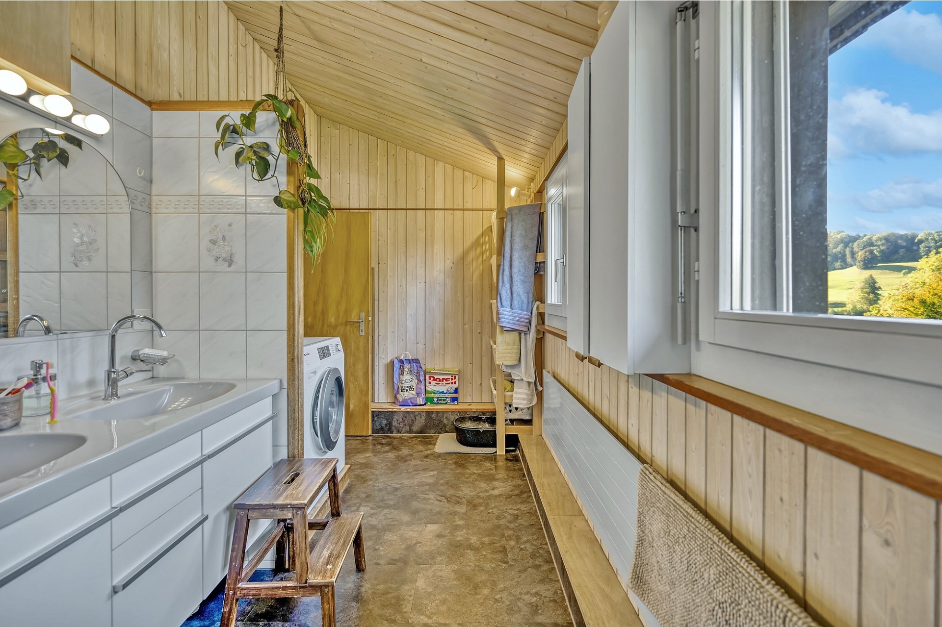 Helles Badezimmer mit Holzverkleidung und Blick ins Grüne