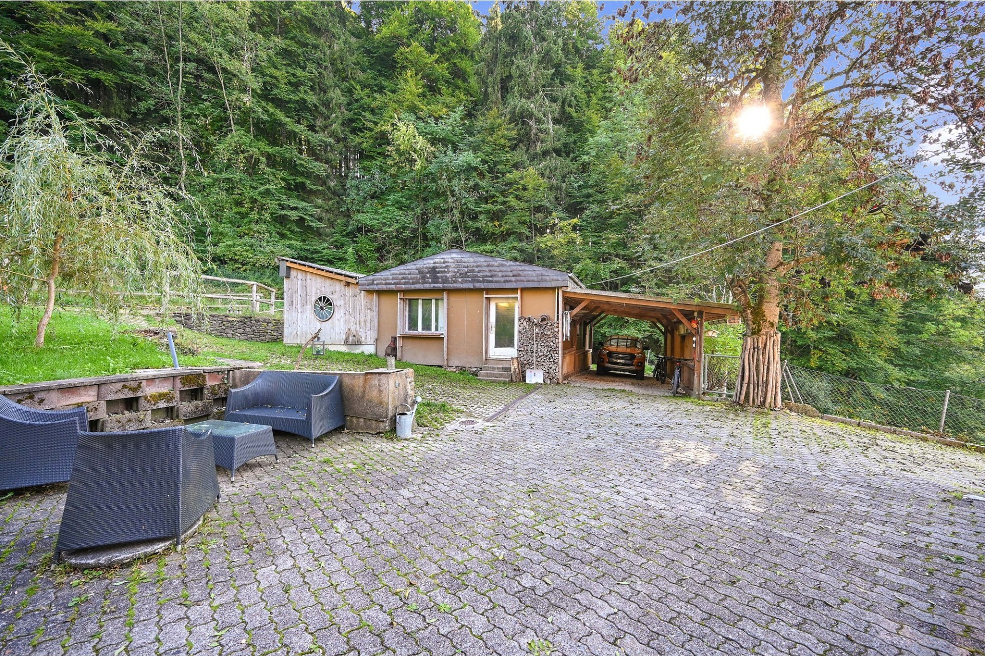 Außenansicht eines kleinen Hauses mit Carport in waldiger Umgebung