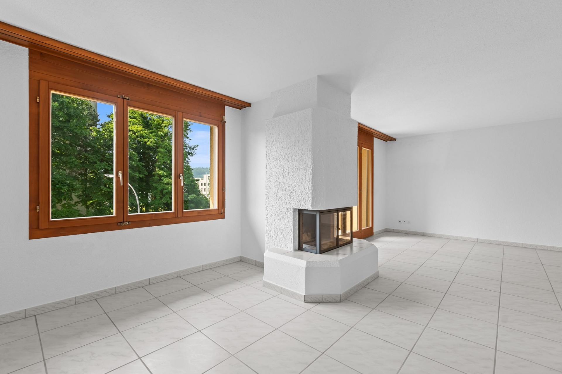 Heller Wohnraum mit Kamin und großen Holzfenstern