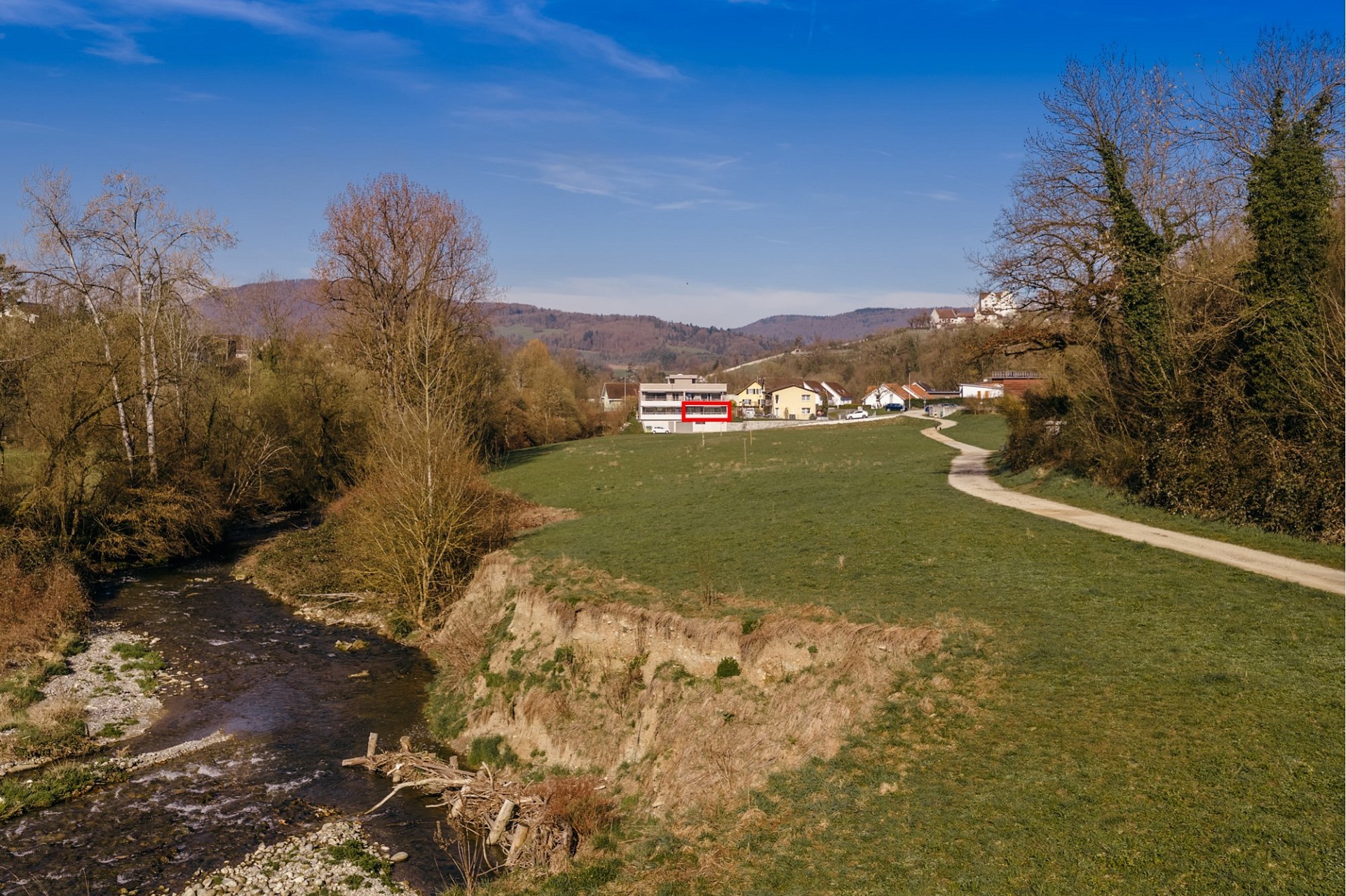 Landschaftsaufnahme mit Bach und Wohnhäusern