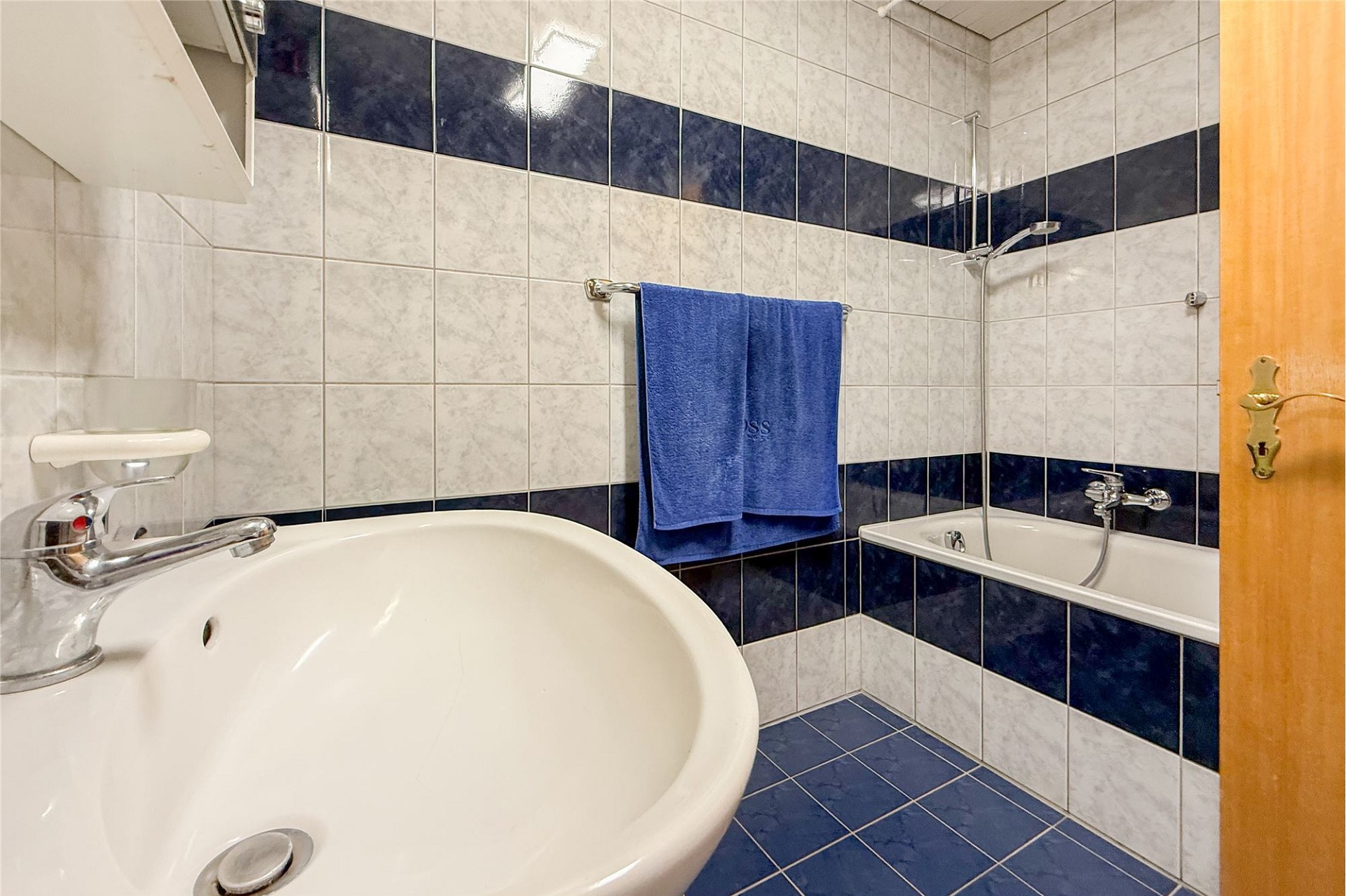Badezimmer mit Badewanne und blau-weißer Fliesenoptik