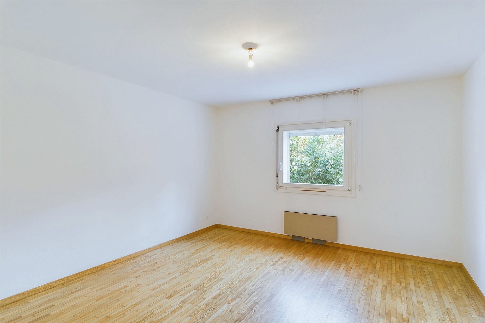 Heller leerer Raum mit Holzfußboden und Fenster