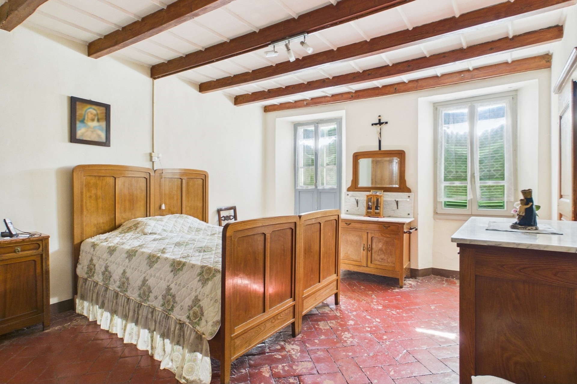 Rustikales Schlafzimmer mit Holzbalken und Fliesenboden