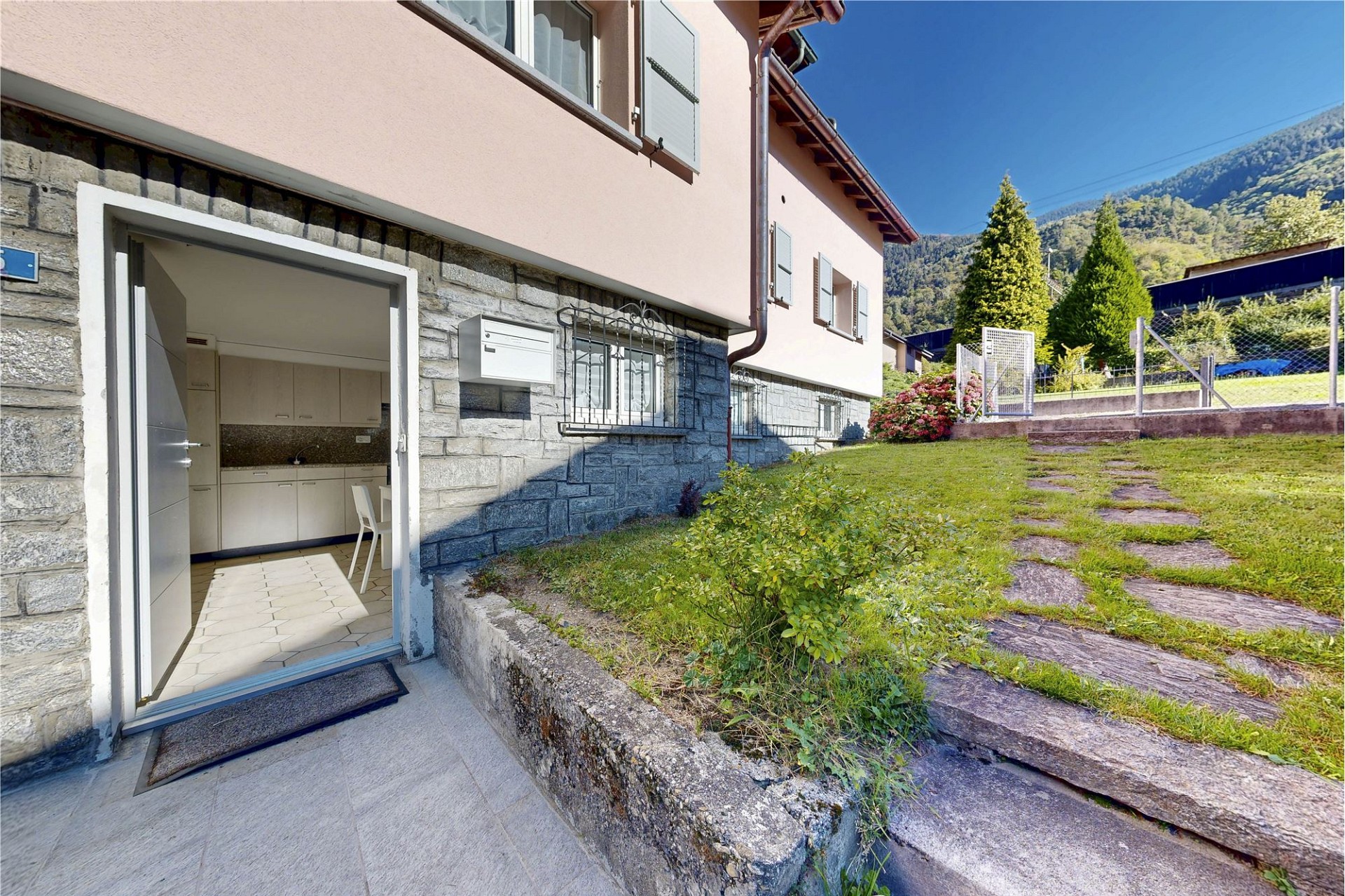 Außenansicht eines Hauses mit Garten und offenem Eingang