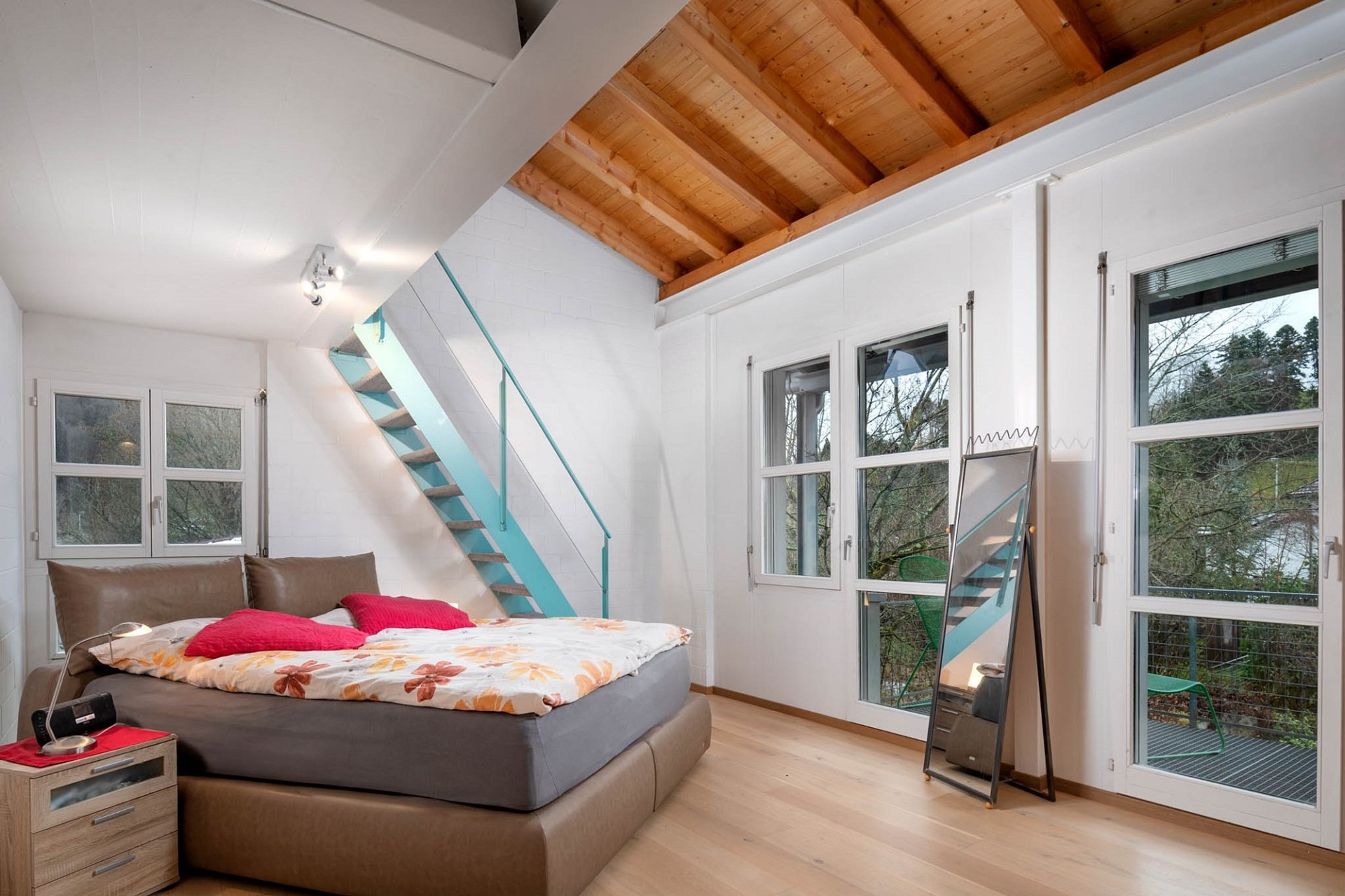 Helles Schlafzimmer mit sichtbarer Holzdecke und Treppenaufgang