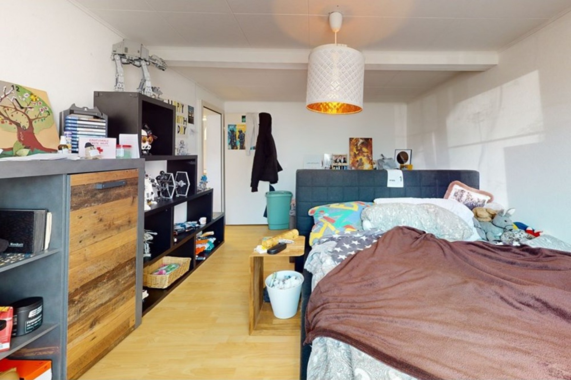 Schlafzimmer mit teilweise ungemachtem Bett und Regalen