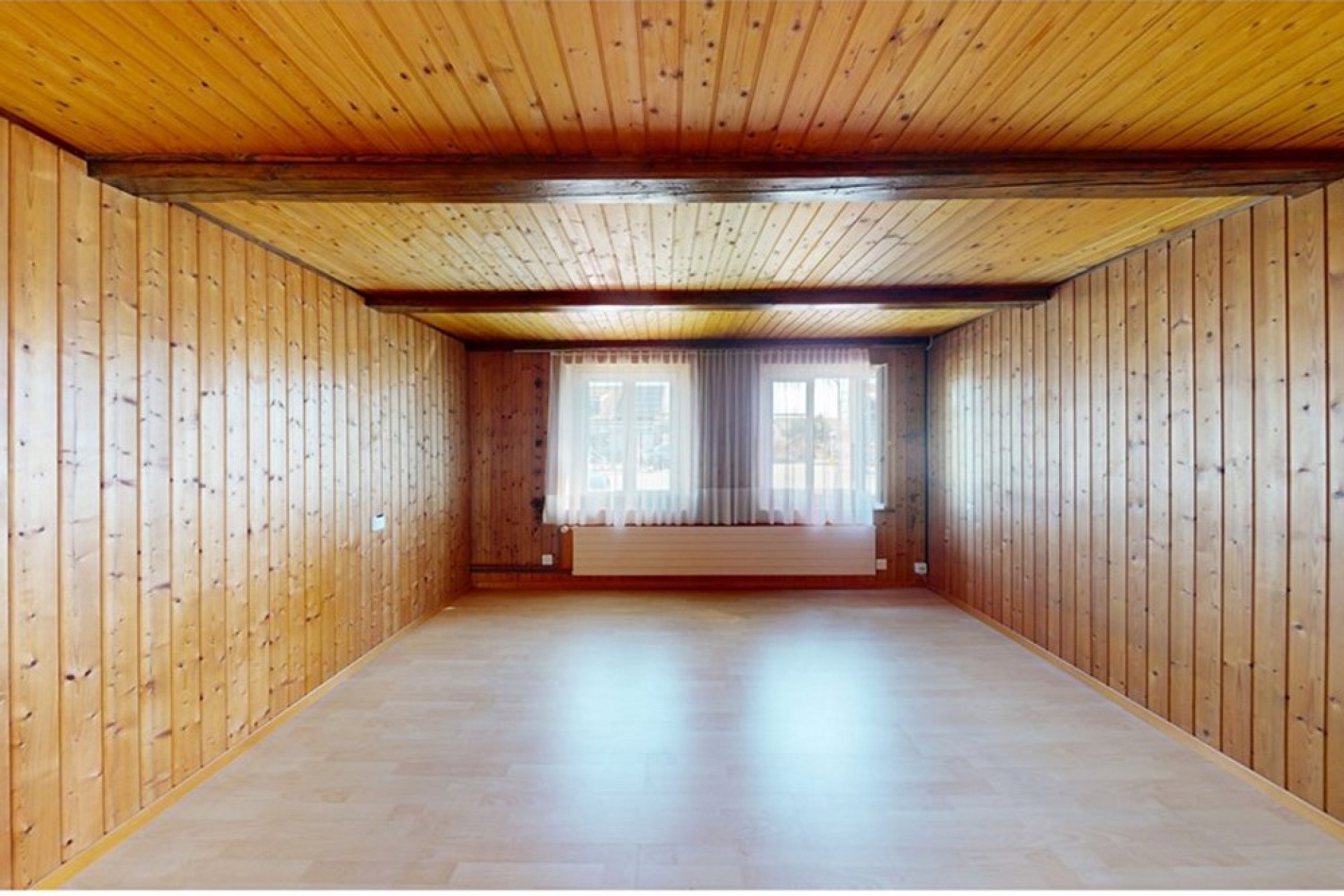 Leerer, holzverkleideter Raum mit Fenster