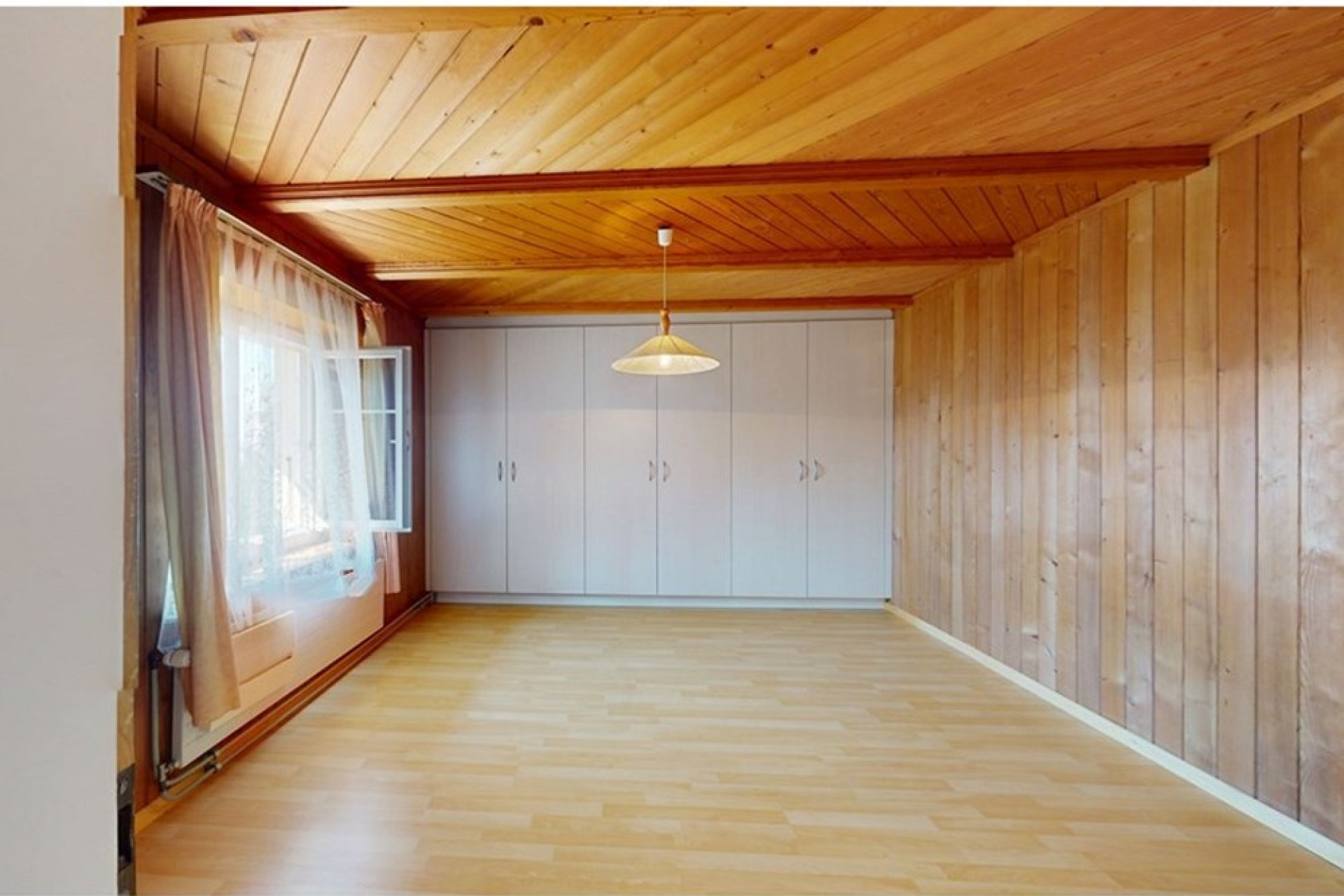 Heller, leerer Raum mit Holzdecke und Einbauschrank