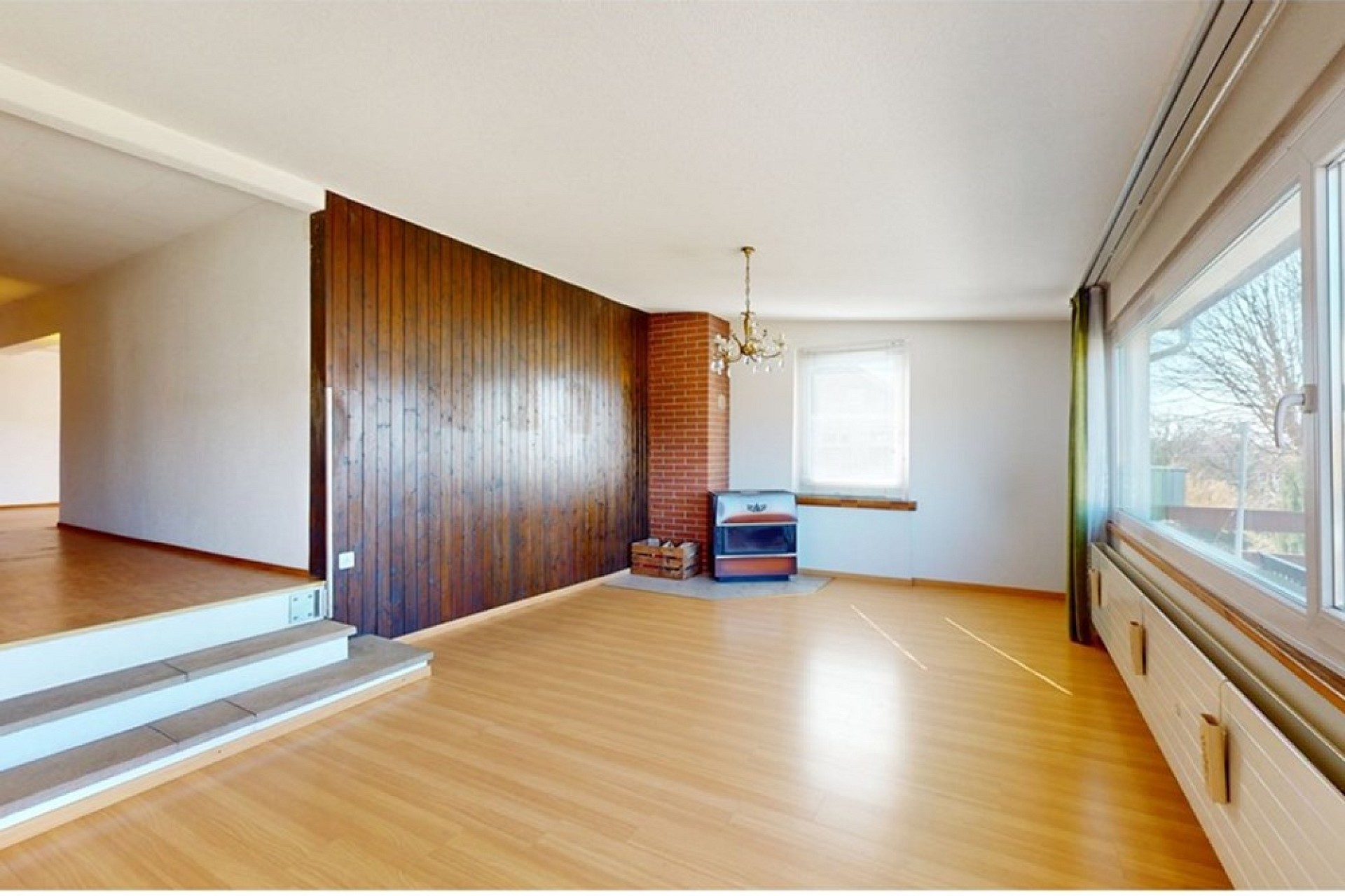 Heller Wohnraum mit Holzpaneelwand und großen Fenstern