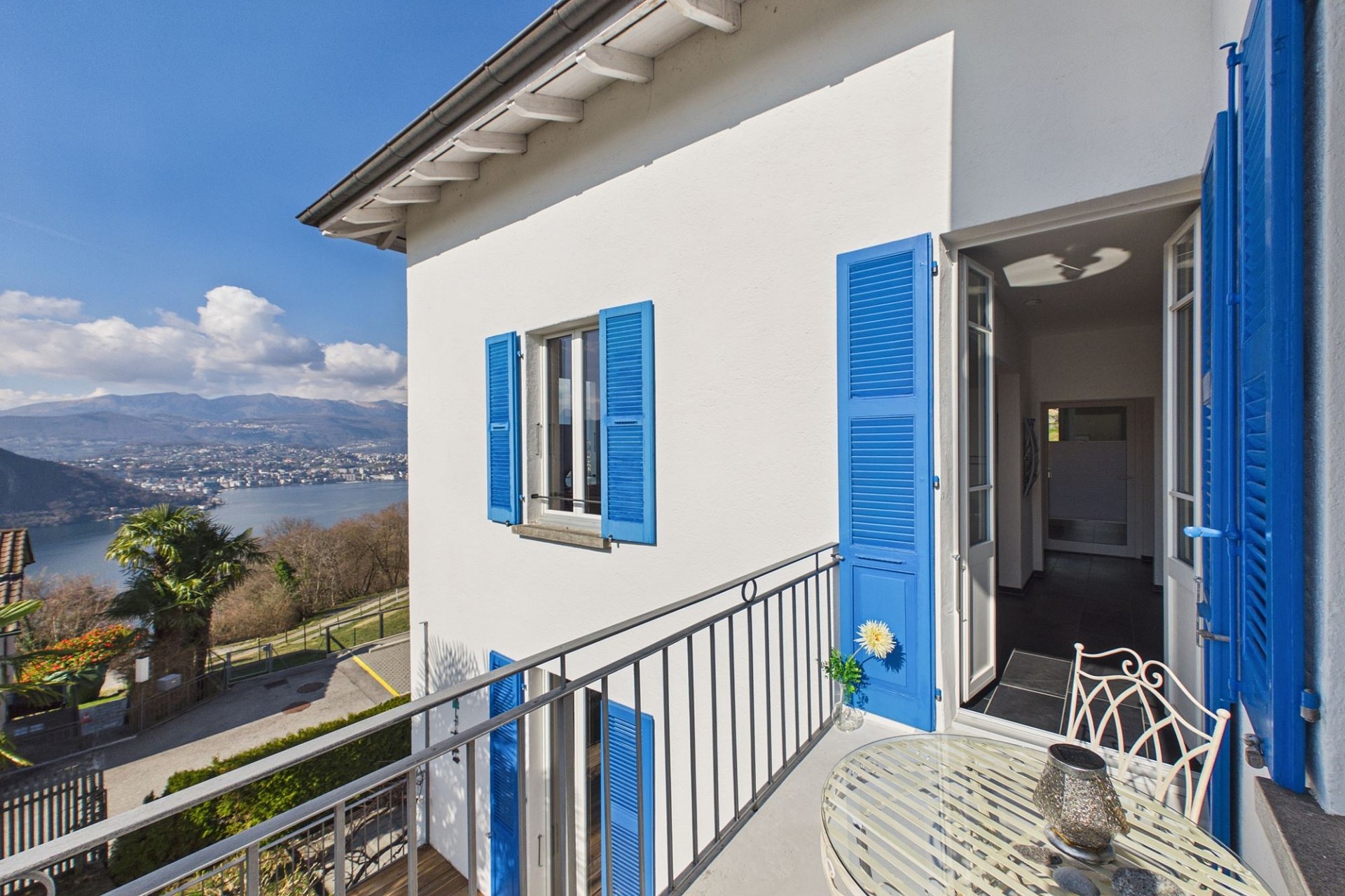 Balkon mit Seeblick und blauen Fensterläden