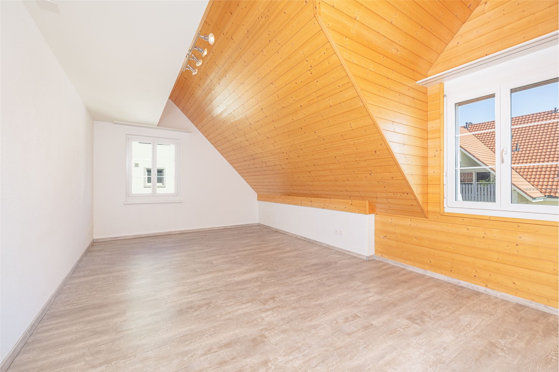 Heller Dachgeschossraum mit Holzdecke und großen Fenstern