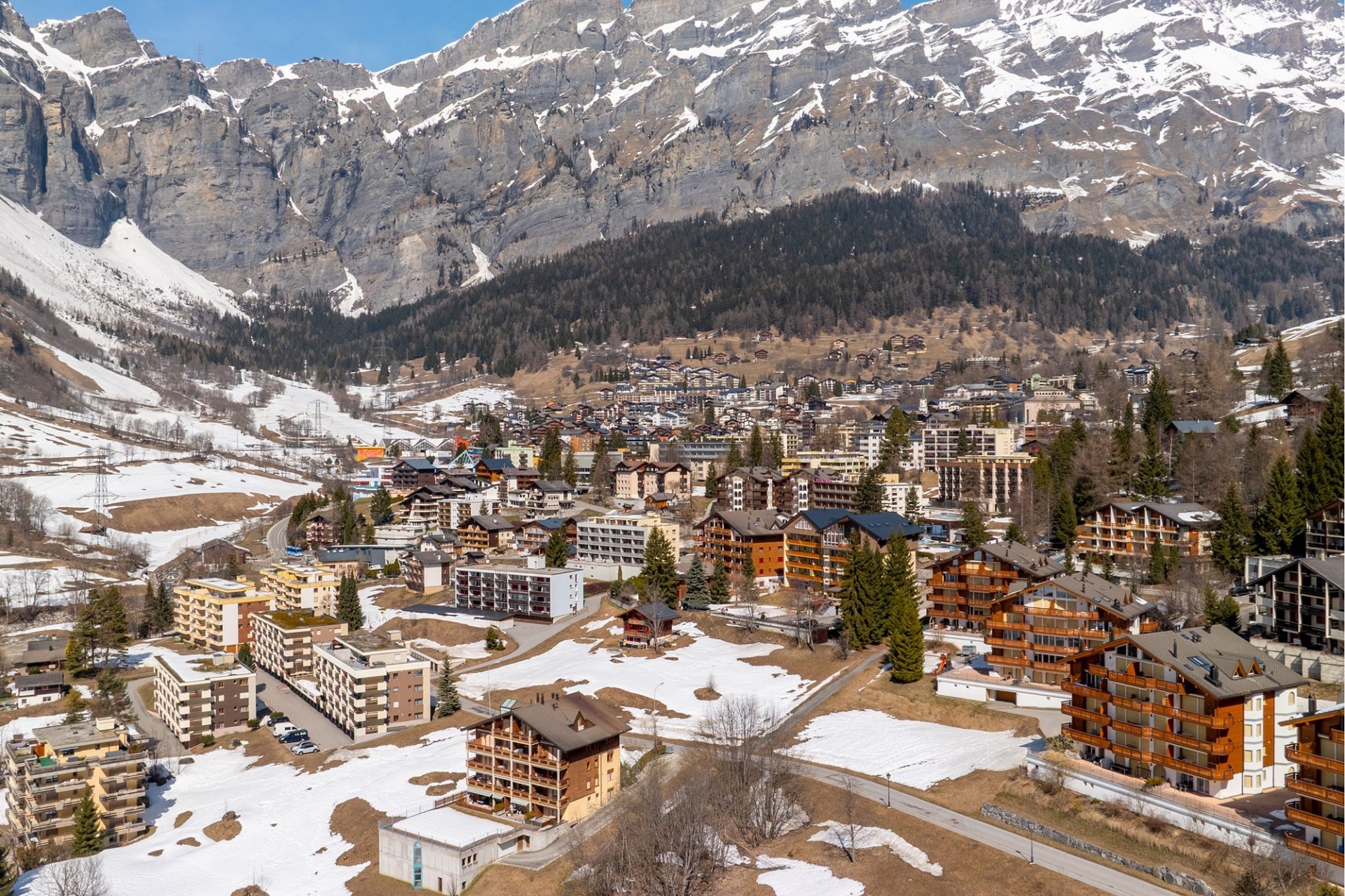 Alpenort mit Berghang und Schneefeldern