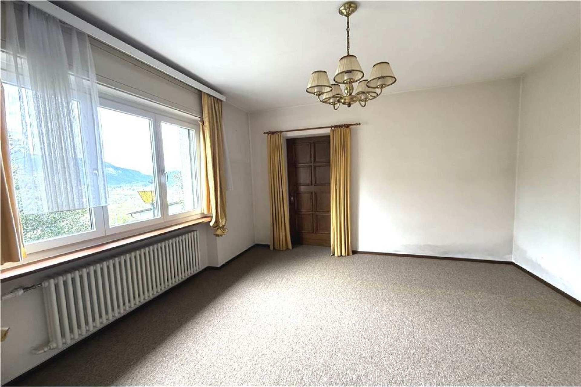 Leerer Wohnraum mit Teppichboden und großem Fenster