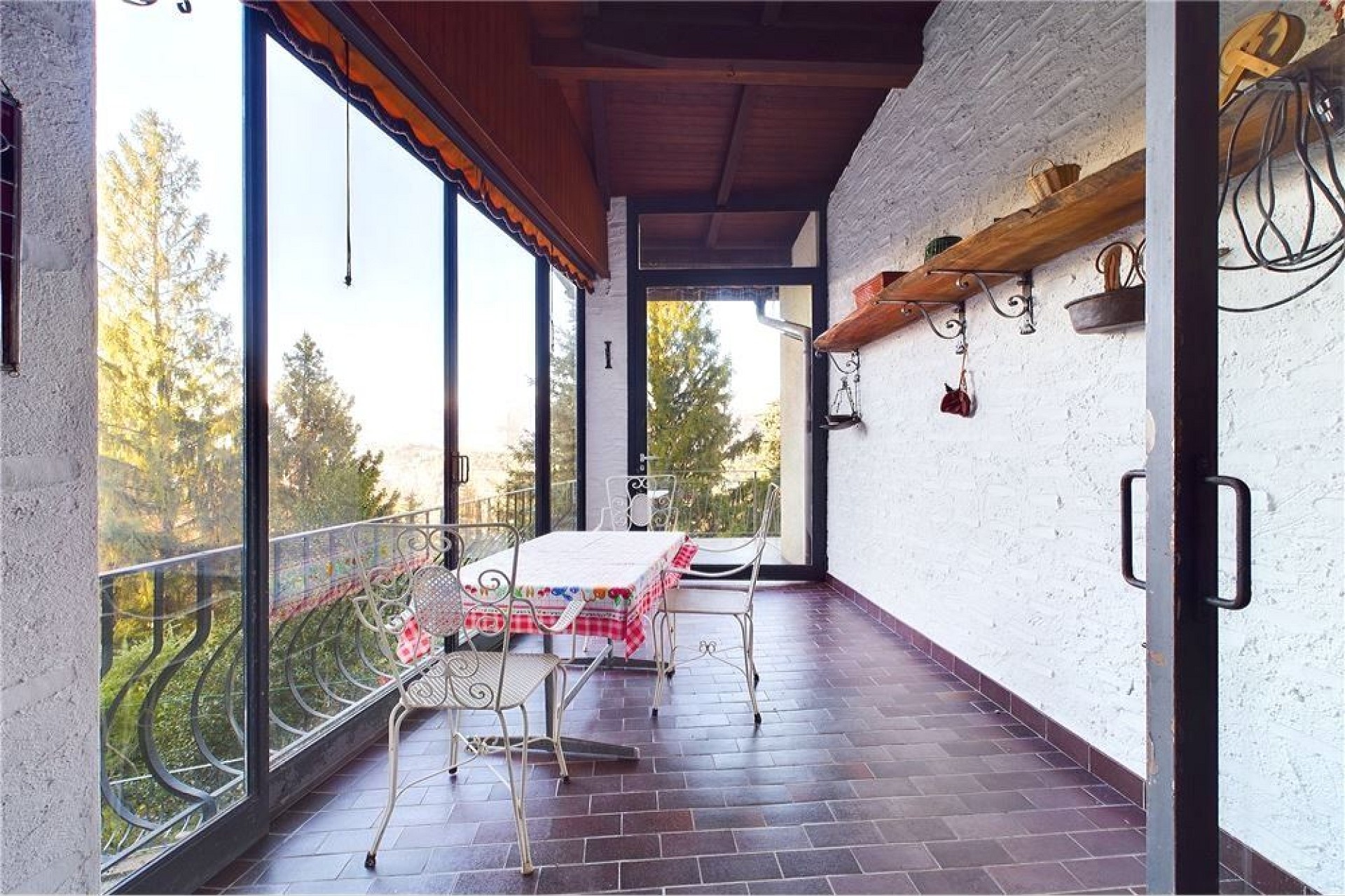 Überdachter Balkon mit Sitzgruppe und Gartenblick