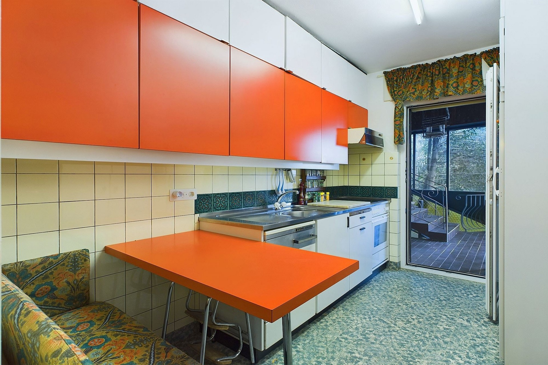Kleine Küche mit orangenen Fronten und Balkonzugang